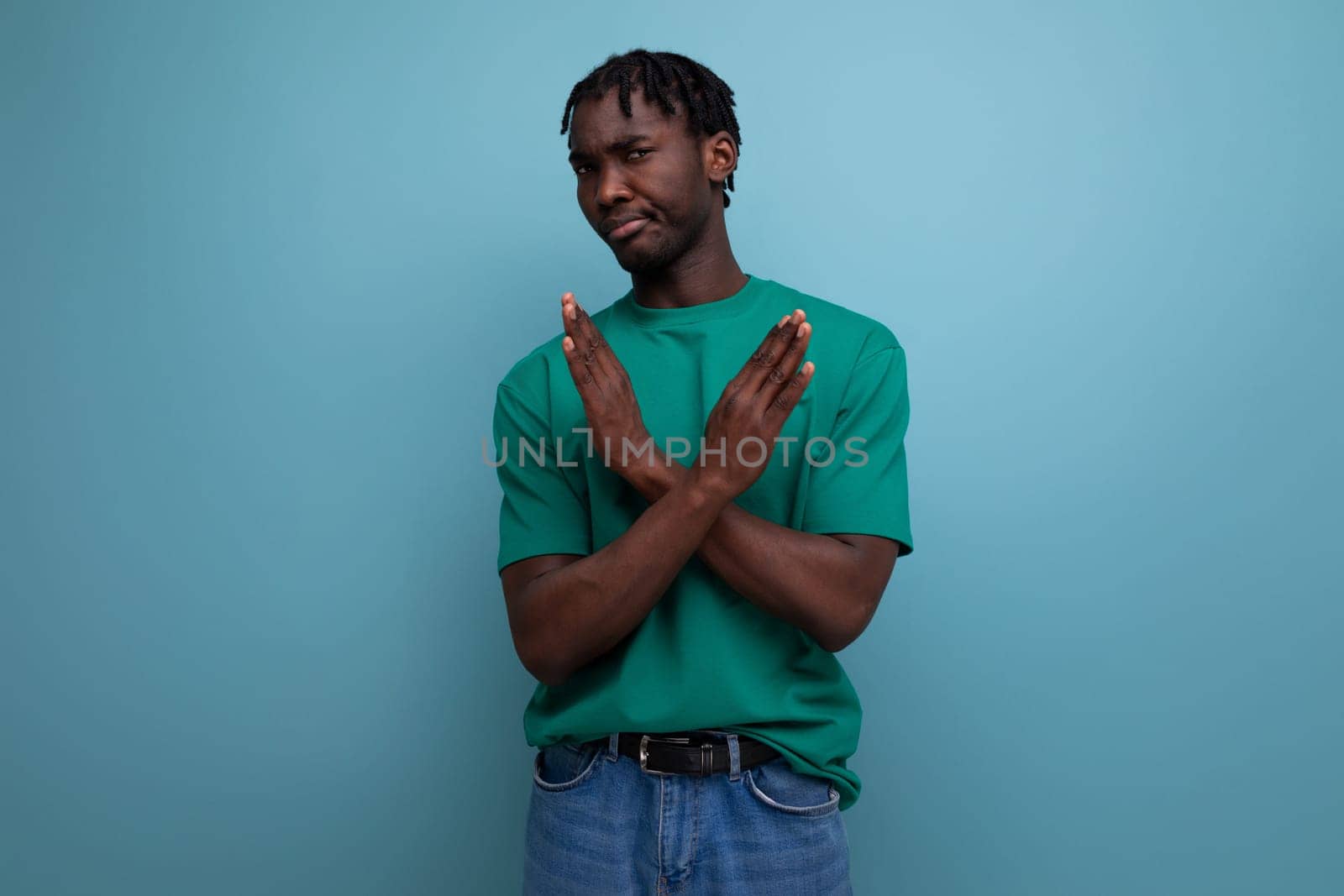 young brunette african man with dreadlocks in a t-shirt with arms crossed.