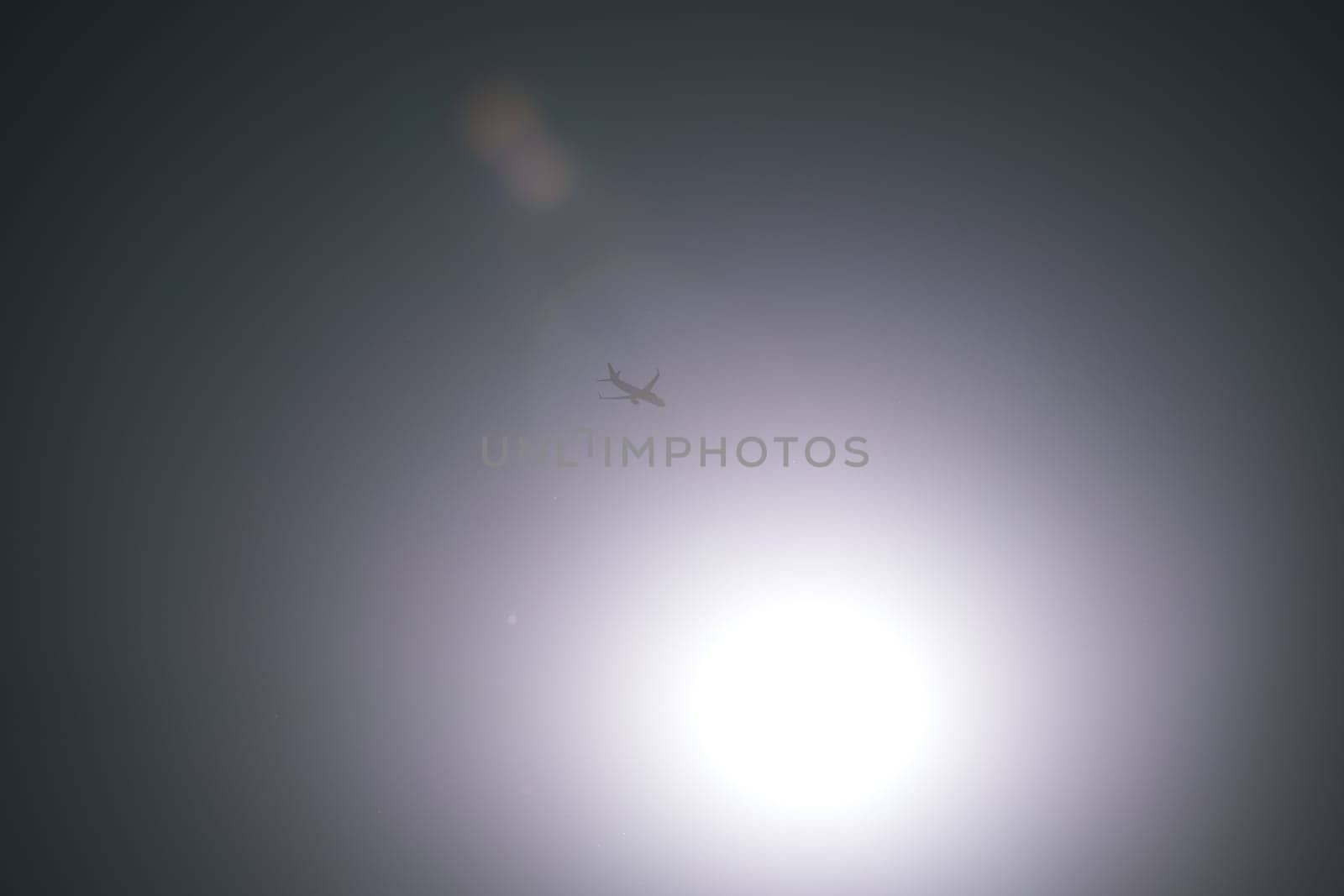airplane in the sky with sun in the sky with sunflare reflection. travel concept. clear weather