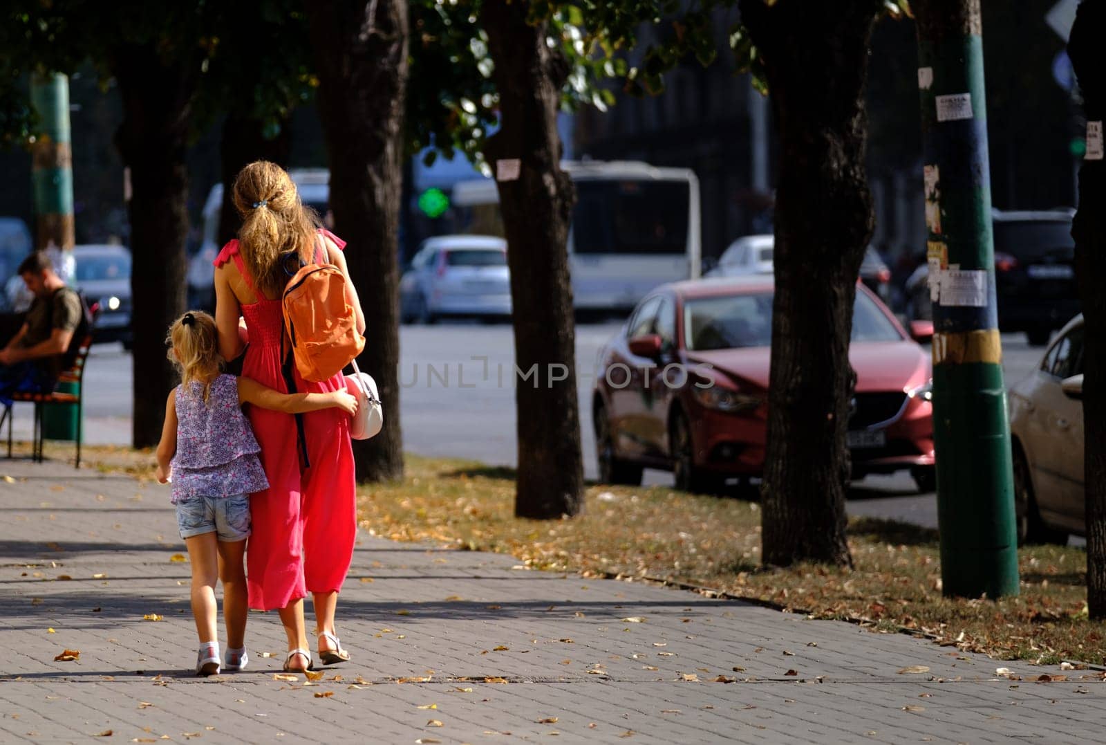 daughter hugs her mom. little girl walking down the street with mom. happy childhood