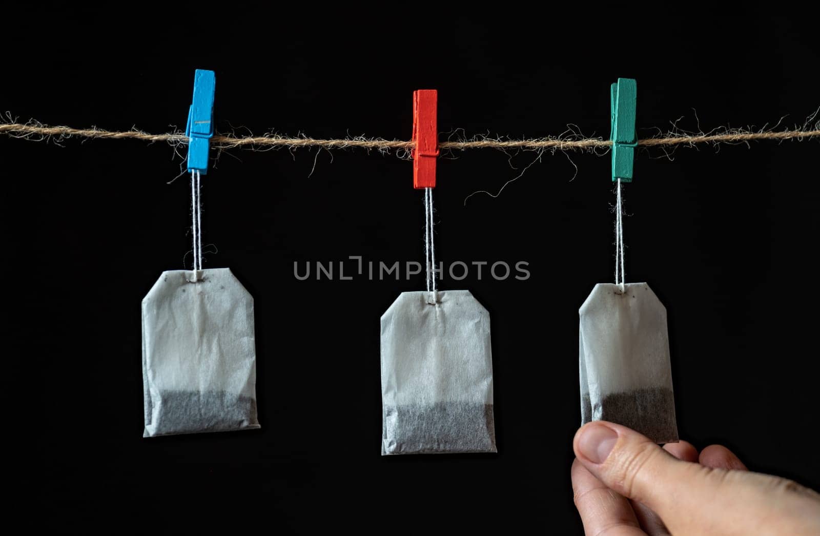 White Tea bags Isolated on background holding on rope, hand pick one. Select best one. best choose of tea concept by igor010