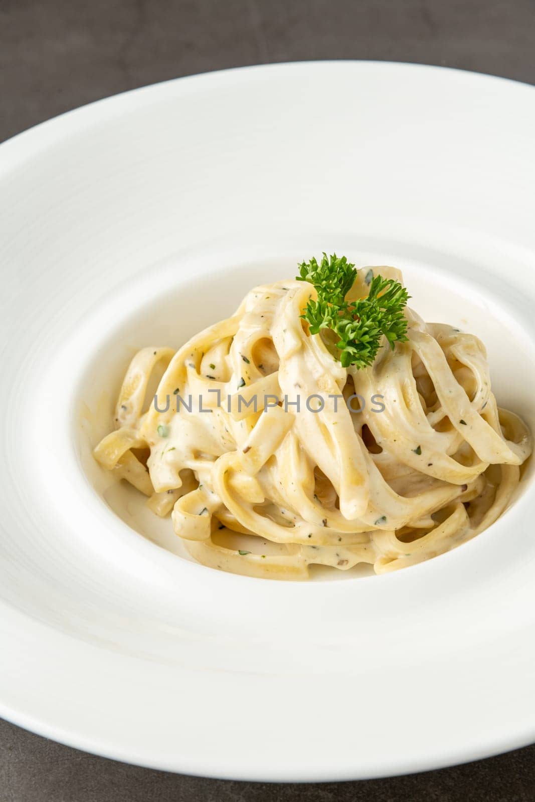 Freshly made fettucini alfredo on a white porcelain plate by Sonat