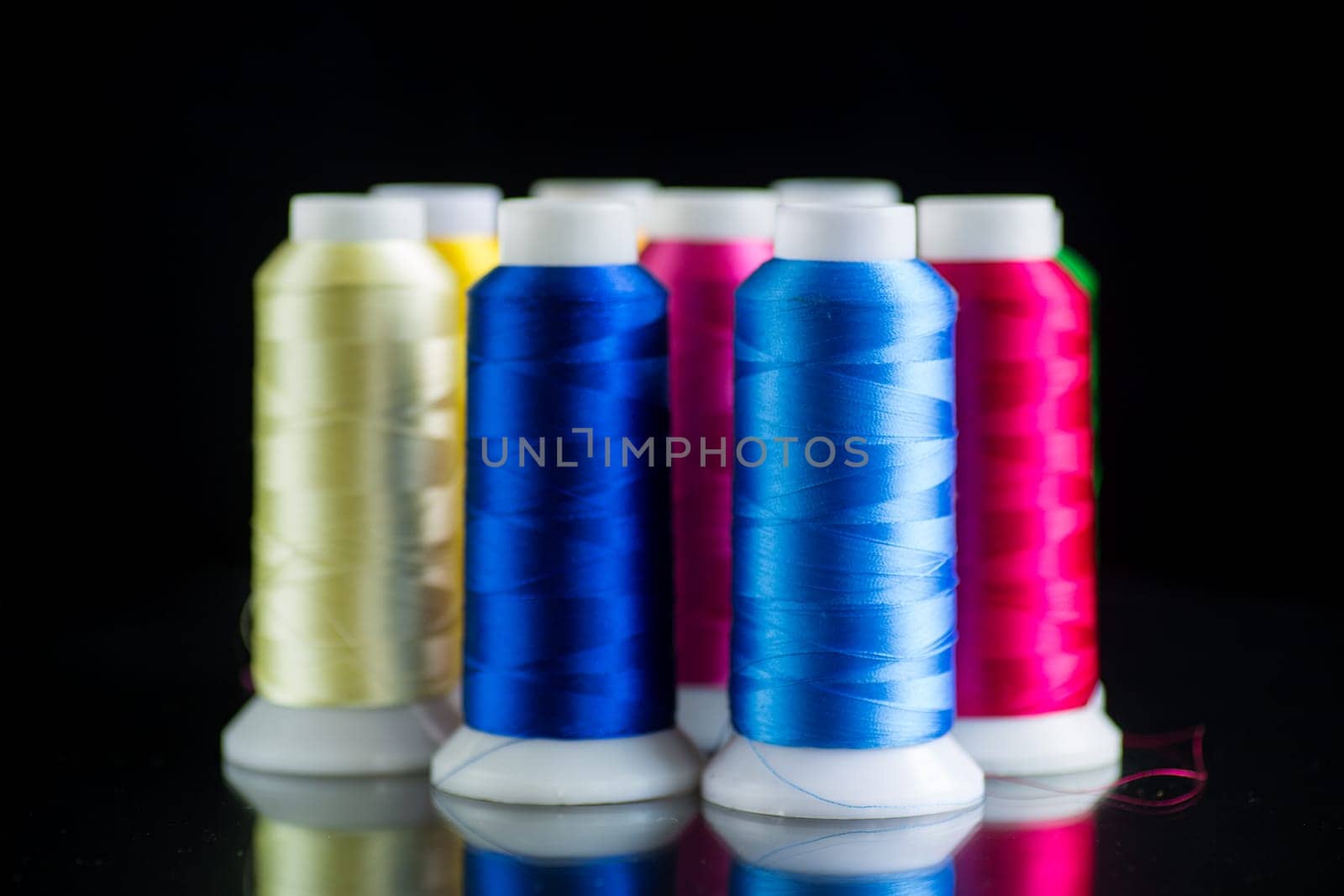 set of different color sewing threads,on black background. by Rawlik