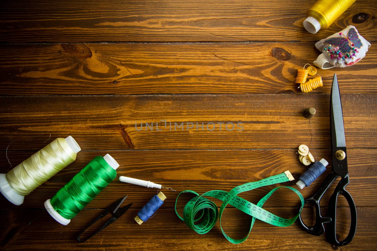 a set of tools and threads for sewing clothes, on a wooden background.