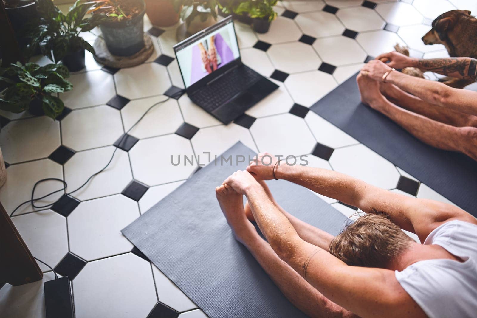 Another day another new yoga video. two men using a laptop while going through a yoga routine at home