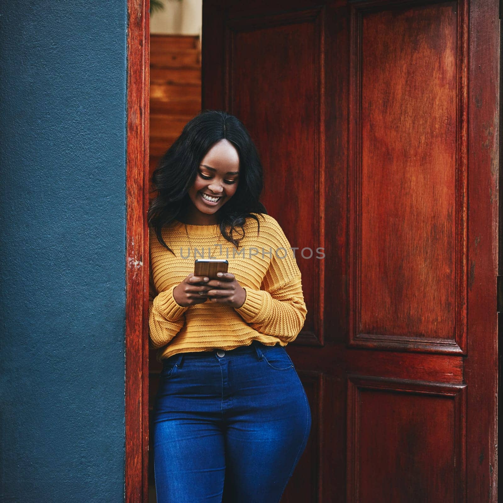 Phone, door and black woman in front of home with social media, smile and streaming or typing. Smartphone, property and female travel influencer with online review for accommodation or rental app.
