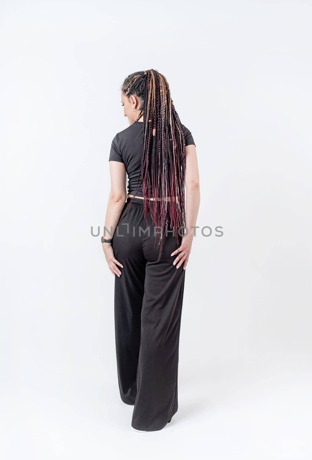 Fashionable young beautiful woman . Slim girl with dreadlocks in an active pose in black pants and top . Fashion, clothing and style.