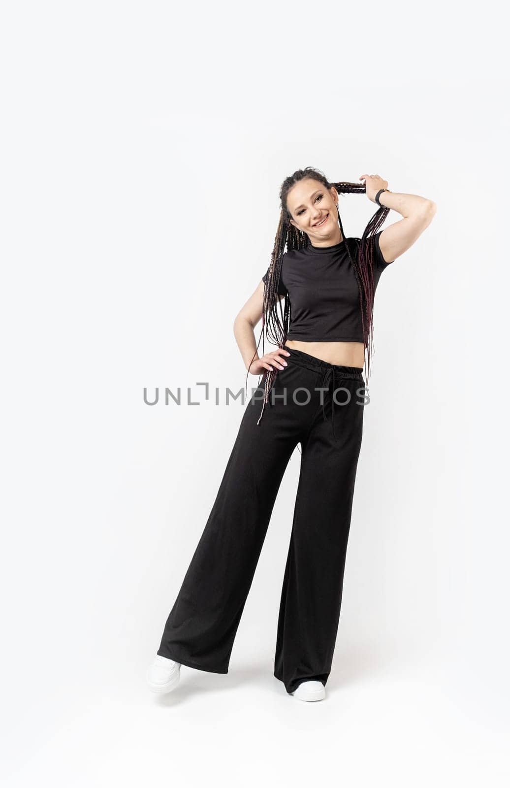 Fashionable young beautiful woman . Slim girl with dreadlocks in an active pose in black pants and top . Fashion, clothing and style.