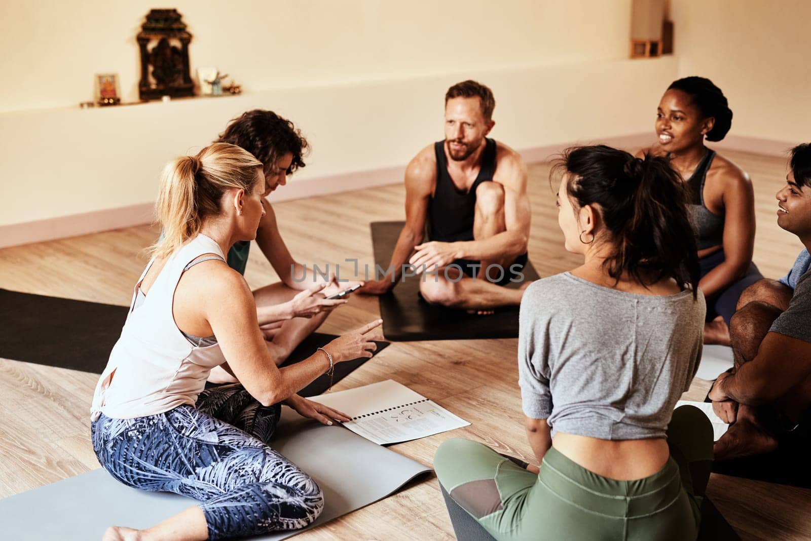 Yoga is even better shared with friends. a group of young men and women chatting during a yoga class