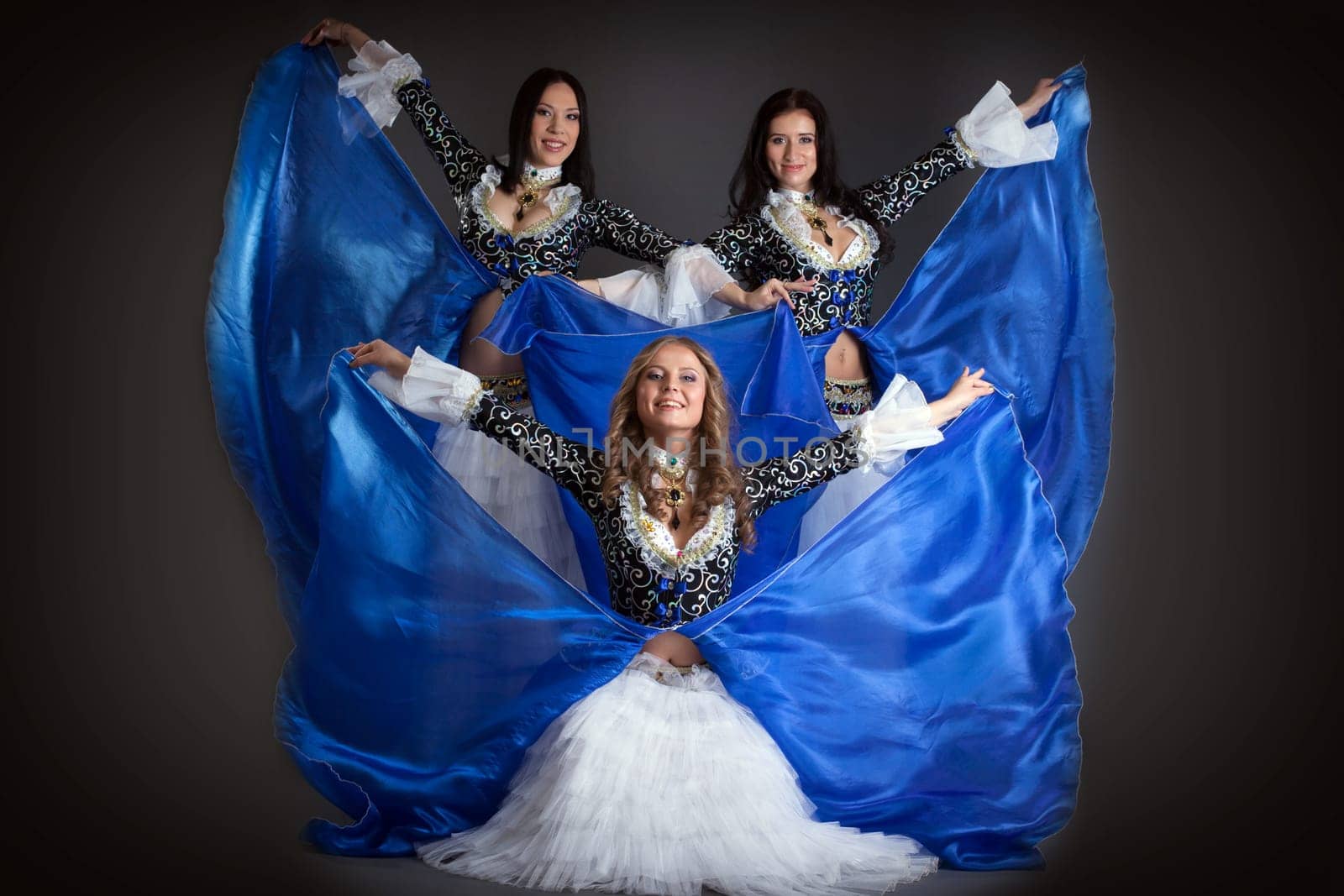 Trio of cute girls in traditional dance costumes posing in studio