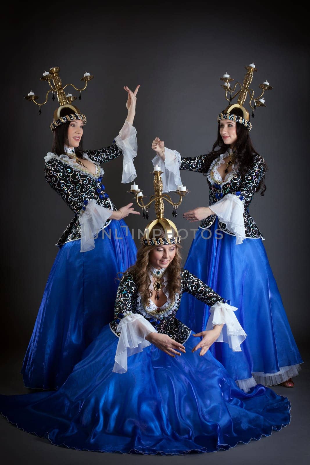 Trio of oriental dancers with candelabras posing in studio