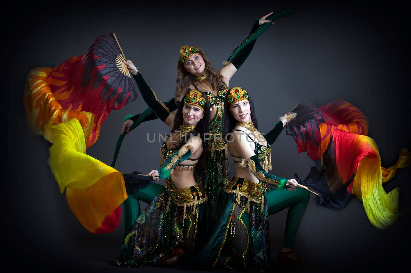 Trio of charming oriental dance performers posing in studio