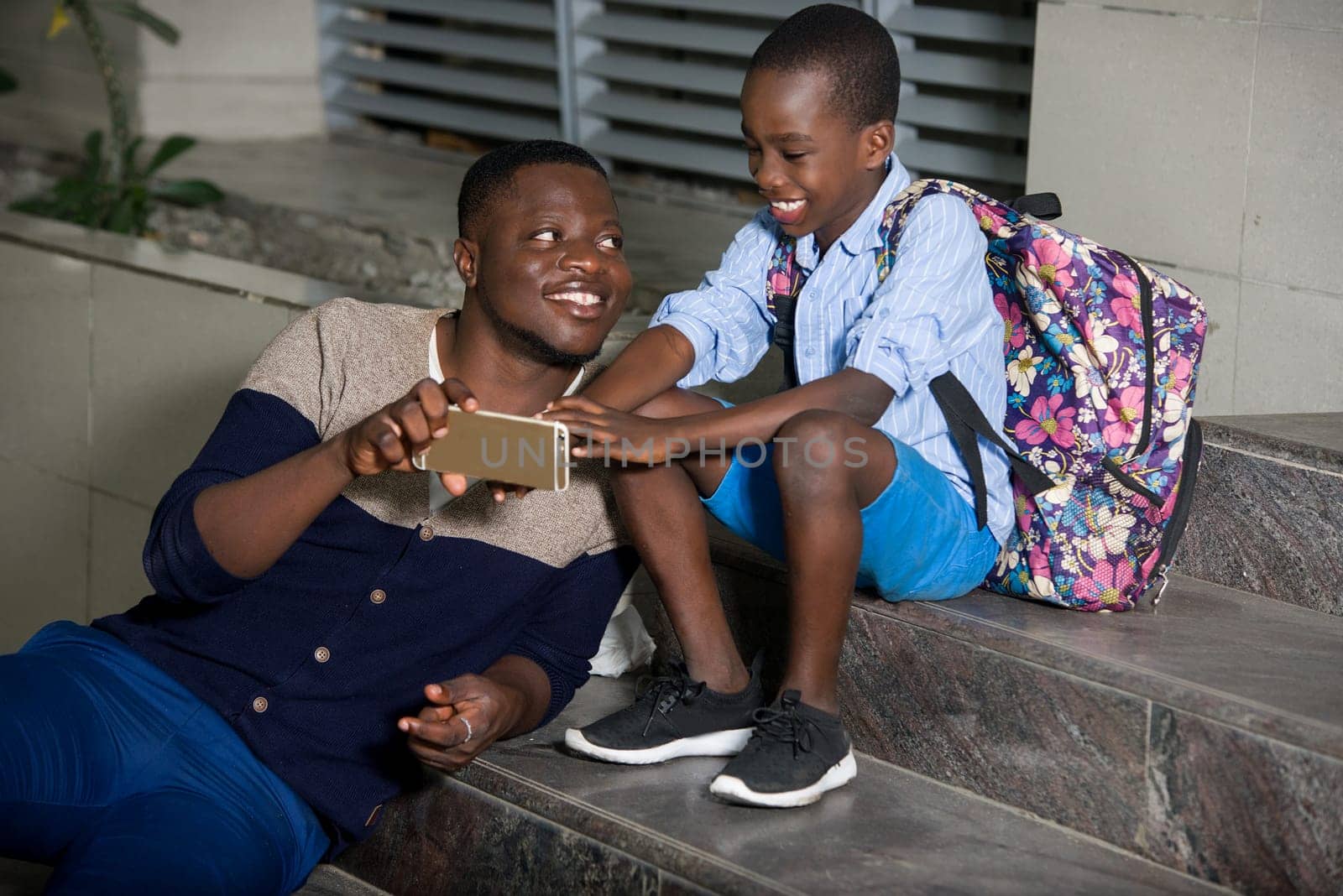 dad and urban son sitting on stairs playing game on smart phone outside, urban happy family concept,