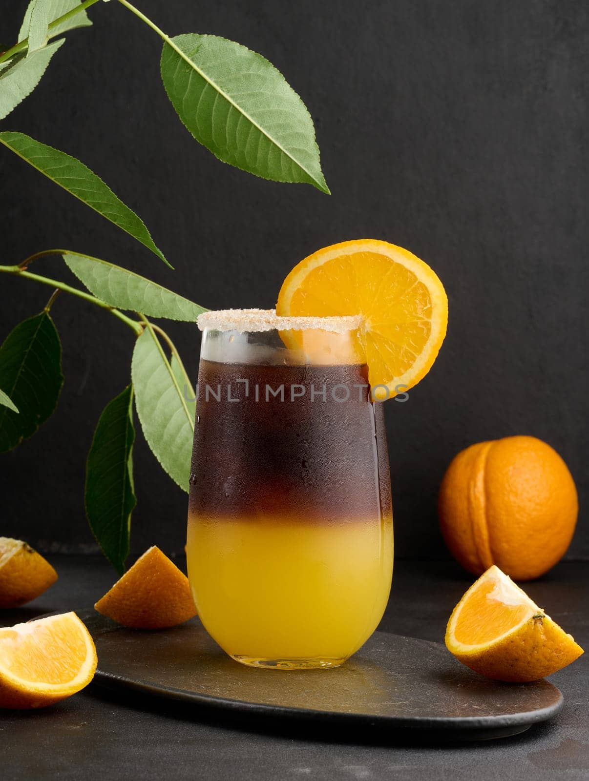 Iced coffee with orange juice in a transparent glass, refreshing bumble coffee on the table