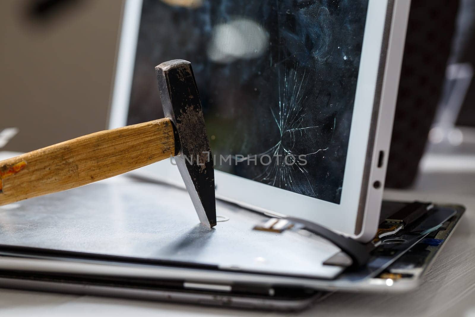 The hammer hits the broken touchscreen tablet, suggesting that it is about to replace it. Broken glass tablet repair