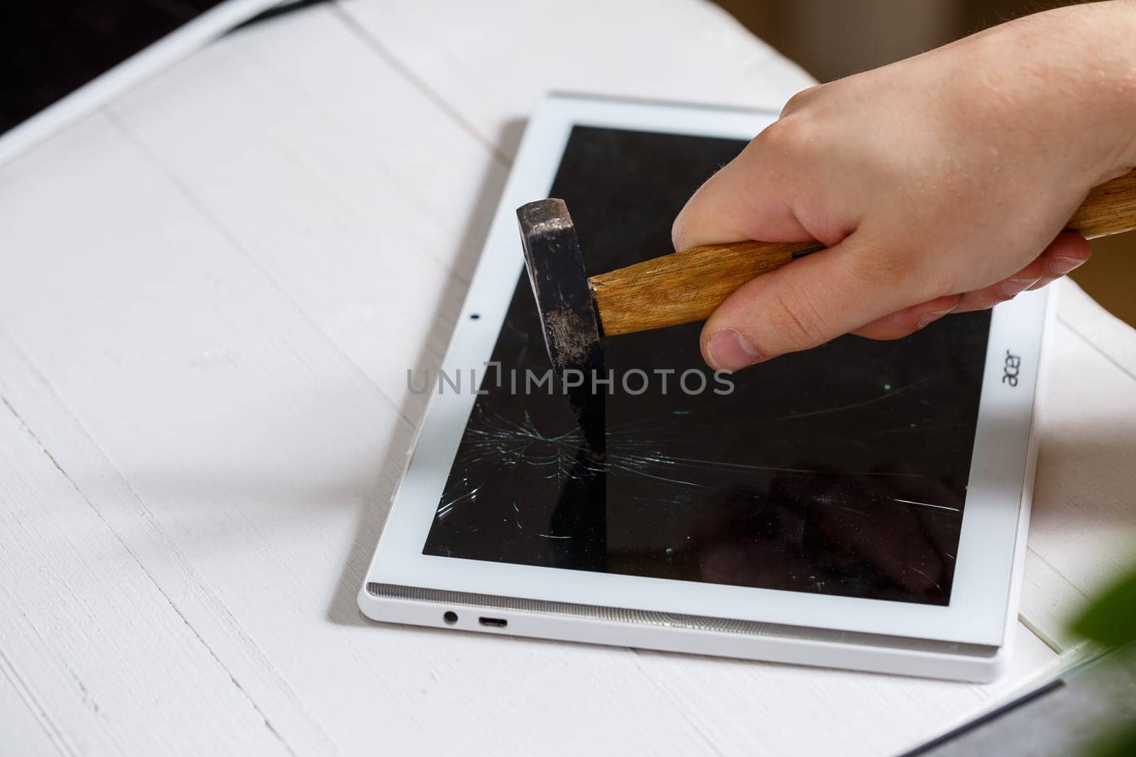The hammer hits the broken touchscreen tablet, suggesting that it is about to replace it. Broken glass tablet repair