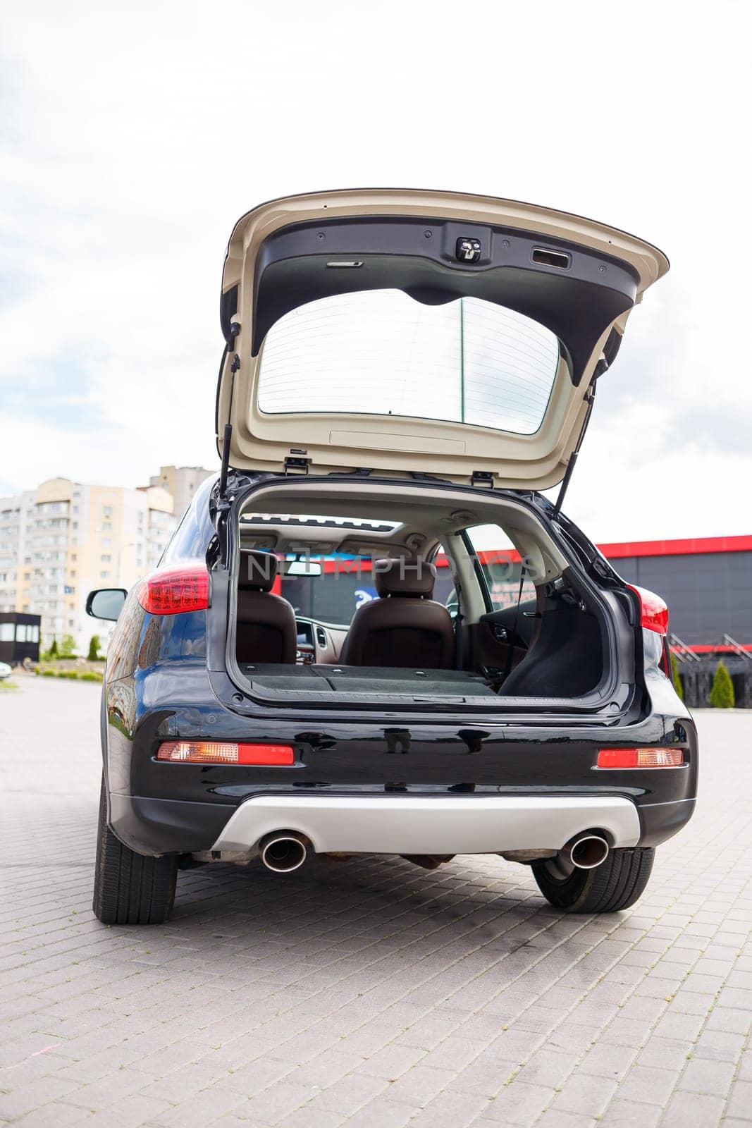 Modern black car, black SUV jeep on big wheels. Rear view of open car trunk