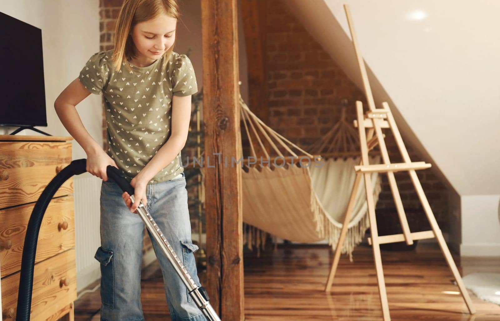 Girl child cleaning carpet with vacuum cleaner from dust at home. Preteen female kid with hoover making order in apartment