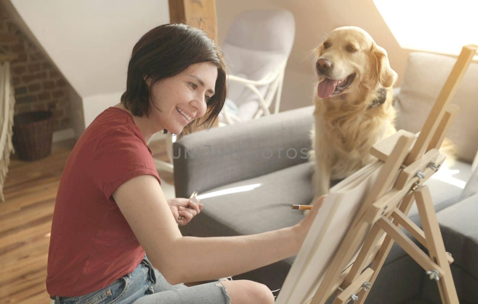 Pretty girl artist drawing sketch with golden retriever dog using pencil and canvas. Beautiful young woman painting portrait of cute doggy pet