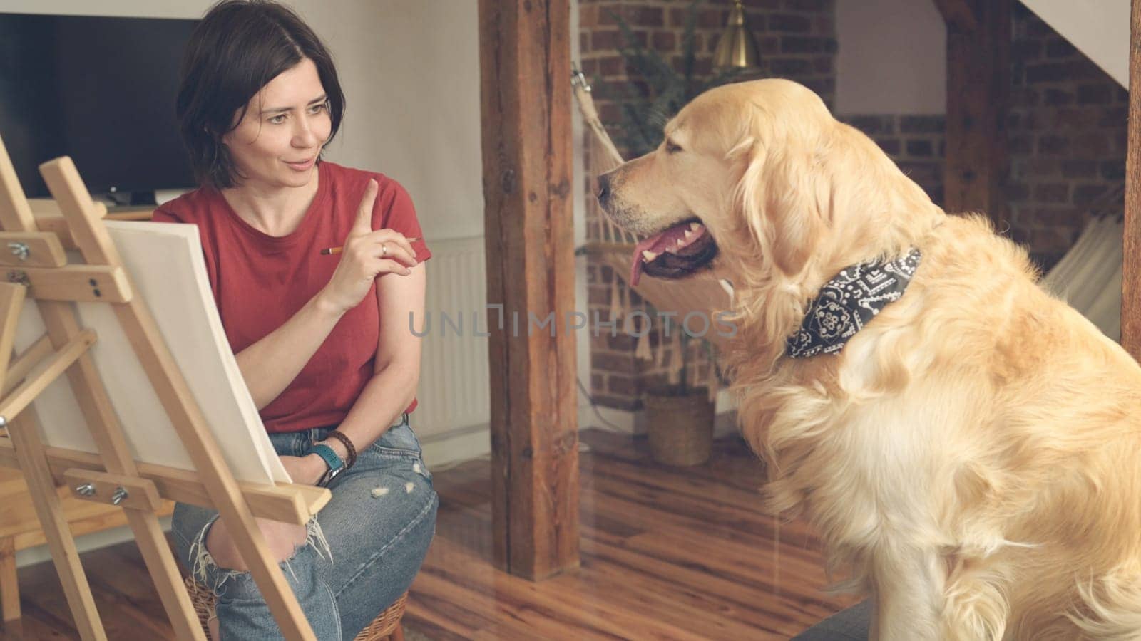 Pretty girl artist drawing sketch with golden retriever dog using pencil and canvas. Beautiful young woman painting portrait of cute doggy pet