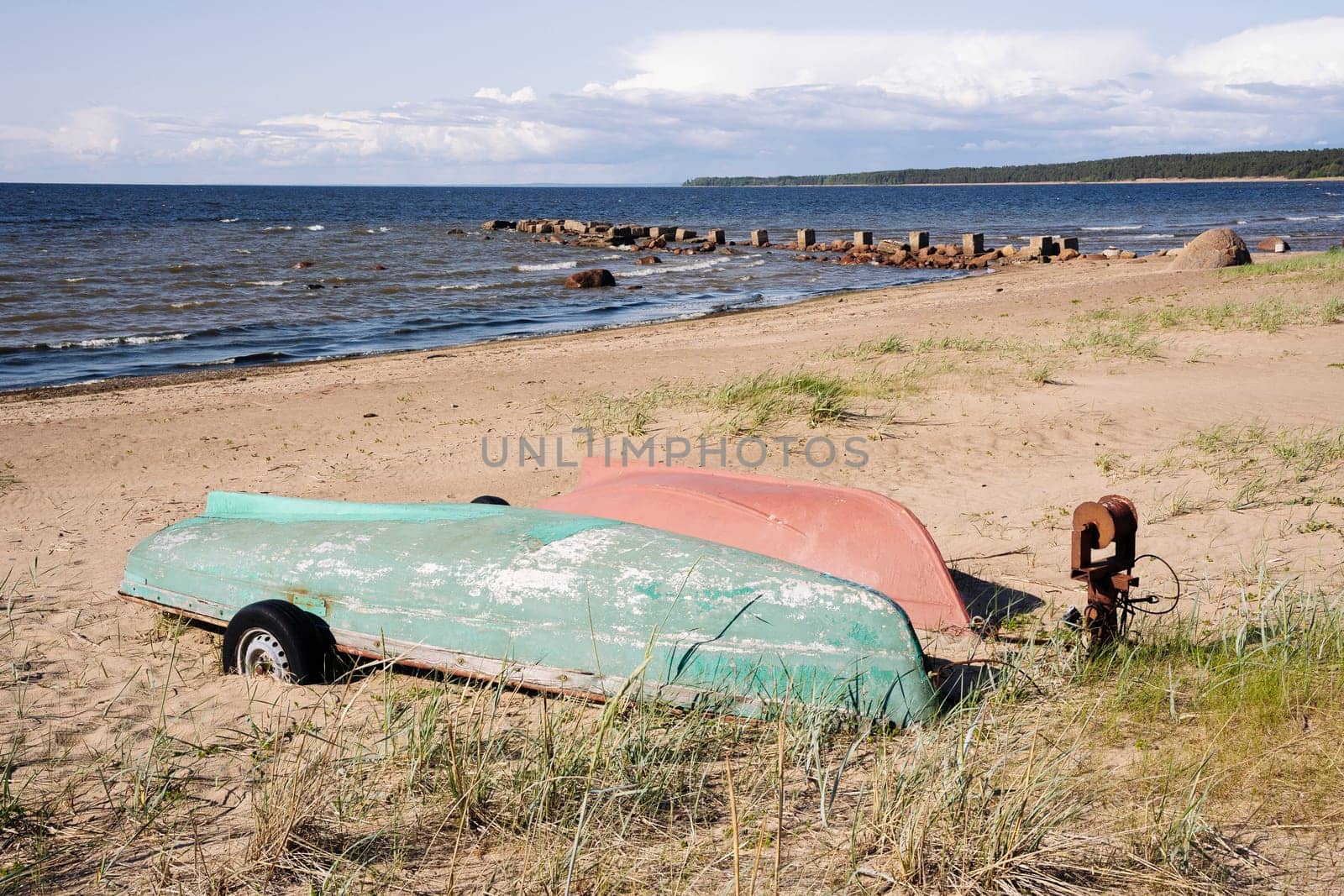 Old fishing boats pulled out on the sandy shore of the sea bay in sunny weather. Fishermen's boats are resting on the shore lying upside down