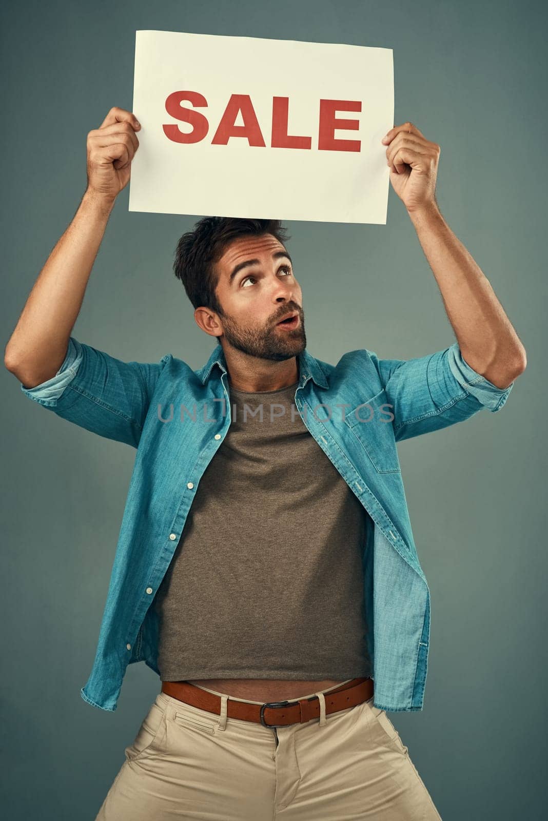 Man, hands and sale on poster for advertising, marketing or branding against a grey studio background. Male person or realtor holding board, sign or billboard for sales announcement or advertisement.