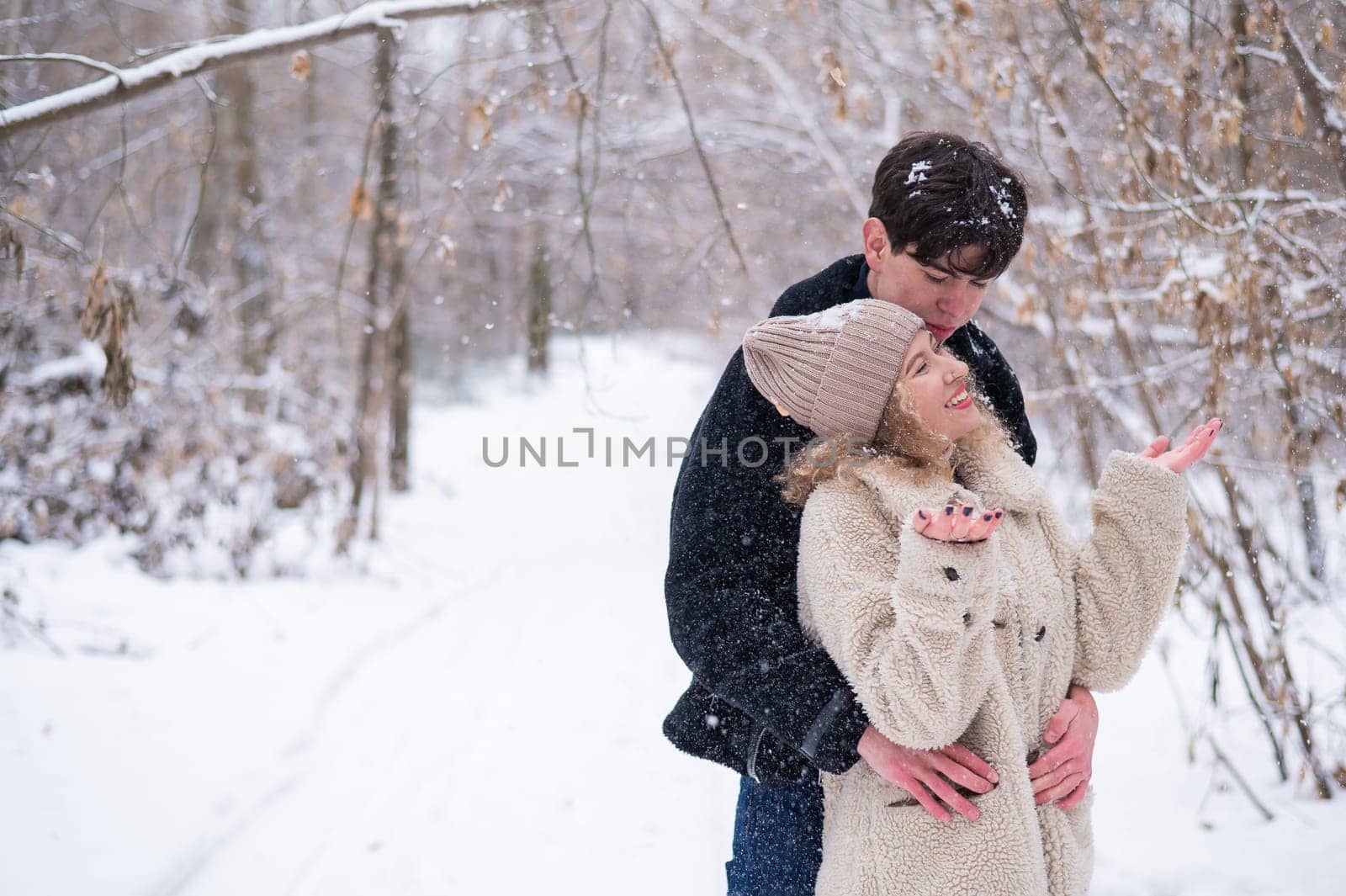 A young couple walks in the park in winter. Guy and girl hugging outdoors. by mrwed54