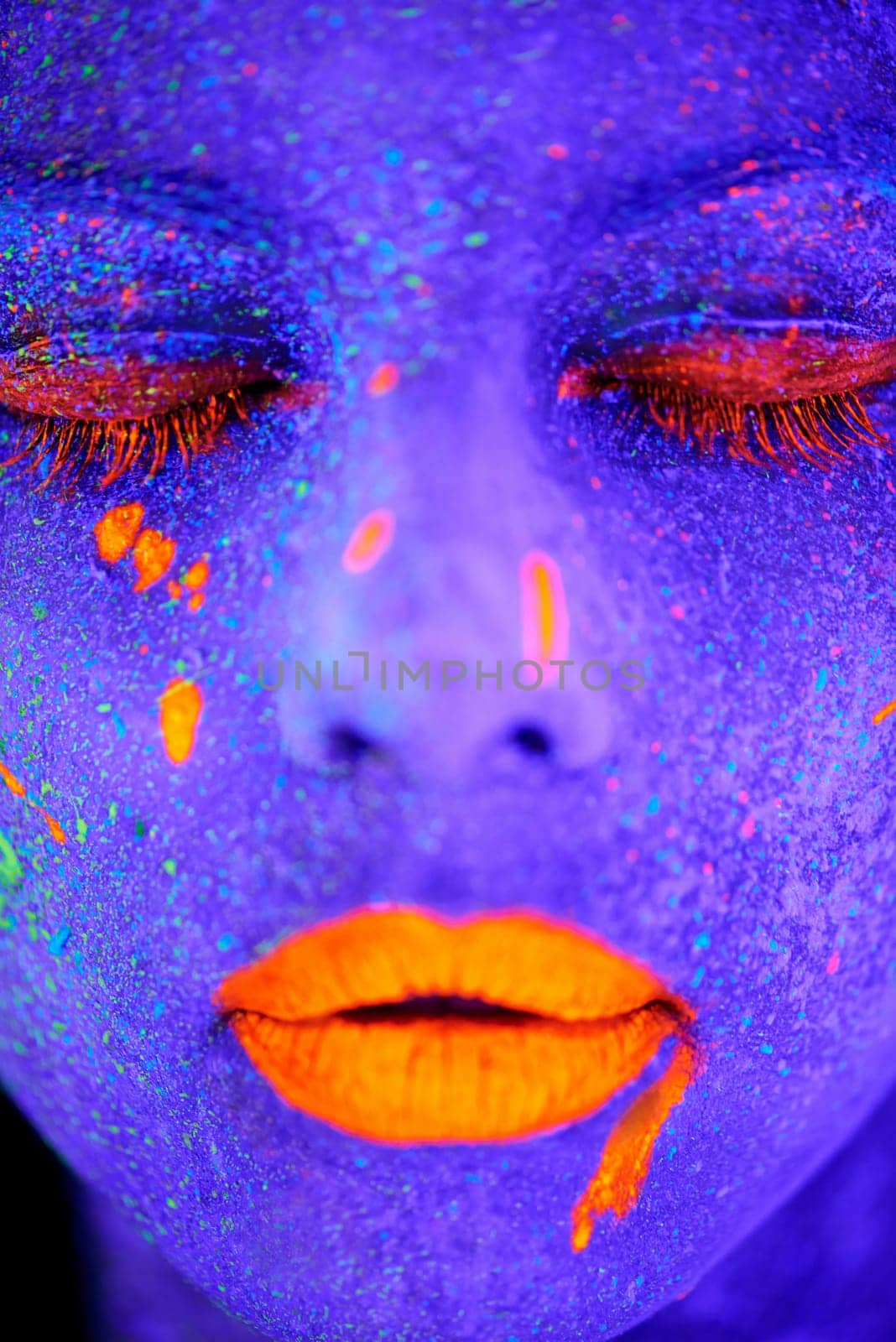 Neon paint, beauty and woman face closeup with dark background and creative cosmetics. Glow, rave makeup and psychedelic cosmetic of a female model with unique and creativity with art in studio by YuriArcurs