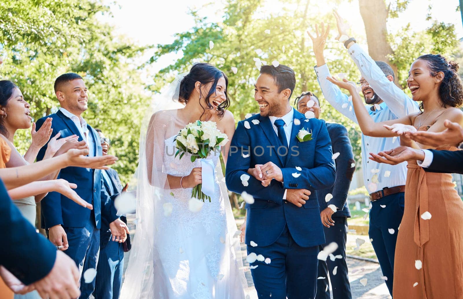 Happy, wedding ceremony and couple walking with petals and guests throw in celebration of romance. Romantic, flowers and bride with bouquet and groom with crowd celebrating at outdoor marriage event. by YuriArcurs