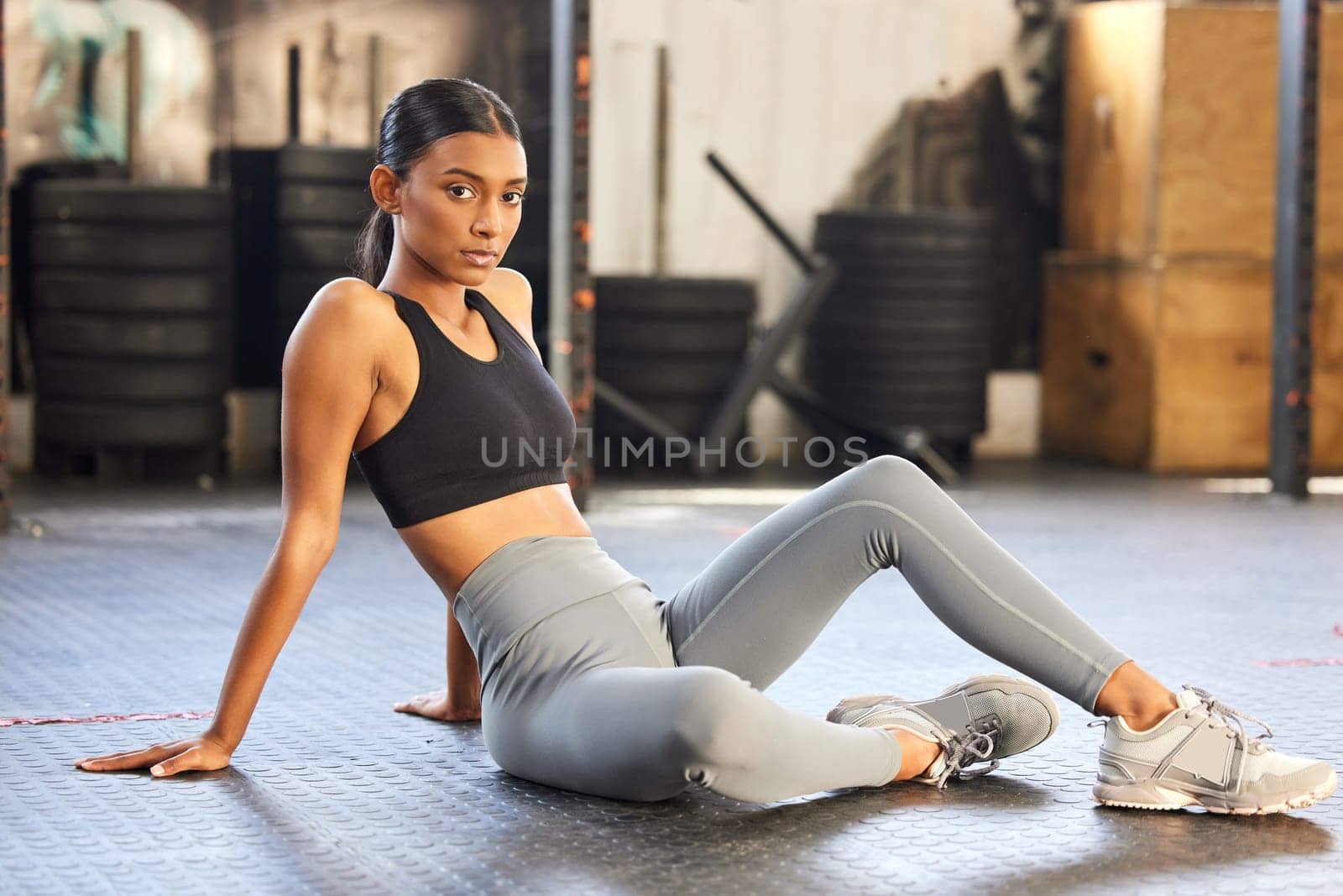 Portrait, fitness or Indian woman on break in gym relaxing ready for sports exercise, workout or wellness. Tired athlete, floor or healthy girl bodybuilder resting for recovery after exercising.