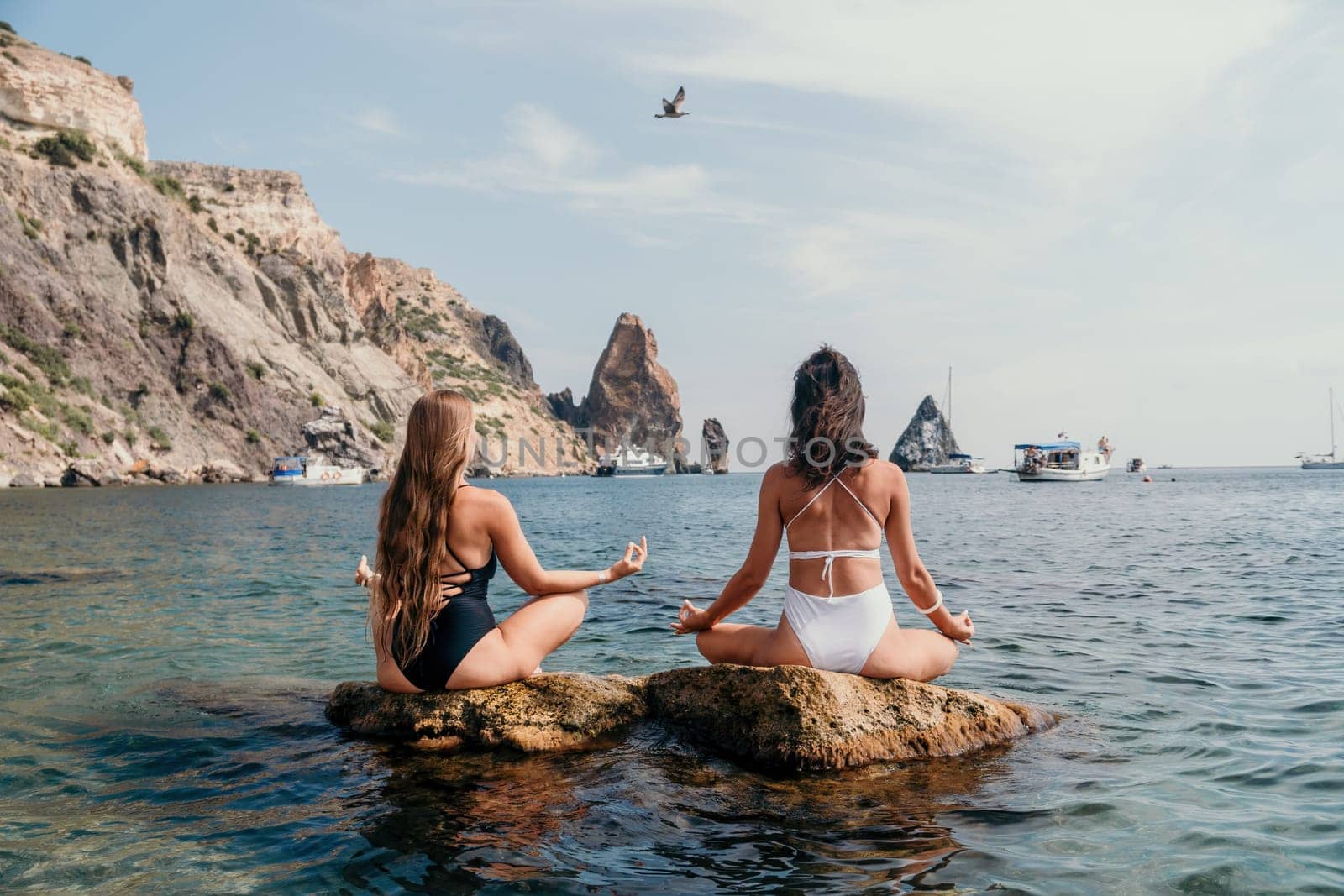 Woman sea yoga. Back view of free calm happy satisfied woman with long hair standing on top rock with yoga position against of sky by the sea. Healthy lifestyle outdoors in nature, fitness concept.