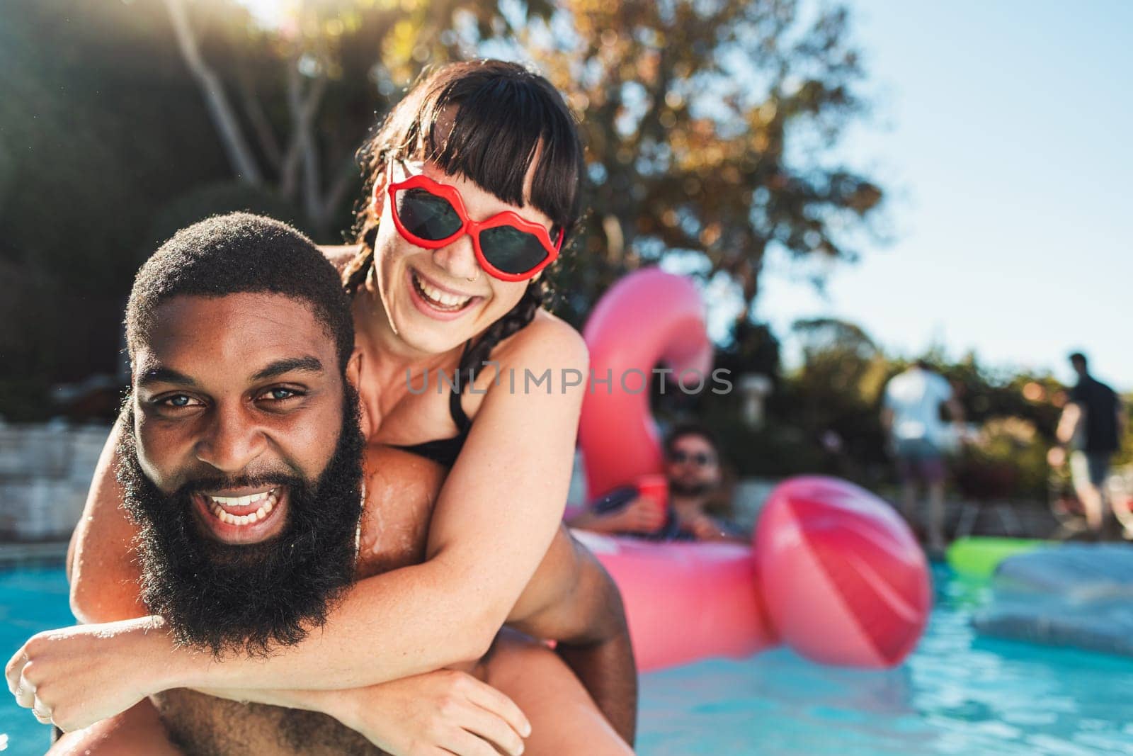 Love, pool party and couple piggyback, having fun and bonding. Swimming, romance diversity and portrait of happy man carrying woman in water and laughing at funny joke at summer event or celebration