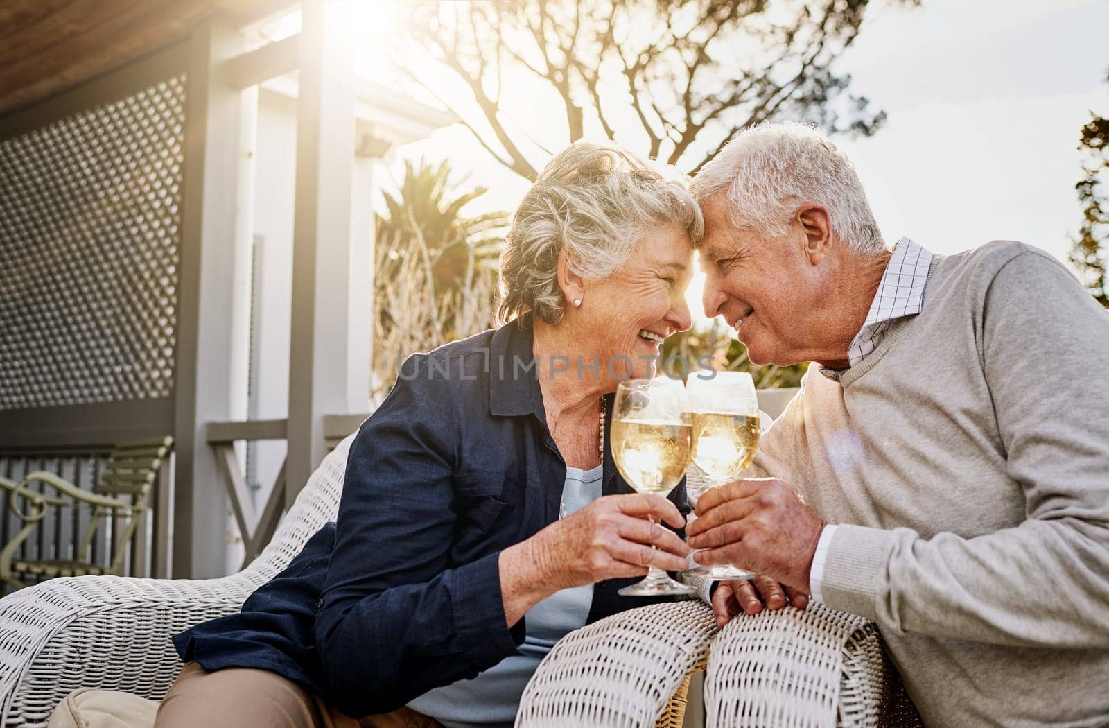 Love, cheers and wine, old couple celebrate romance or anniversary on patio of vacation home. Happiness, senior man and woman touching heads with champagne toast, smile and romantic date on holiday