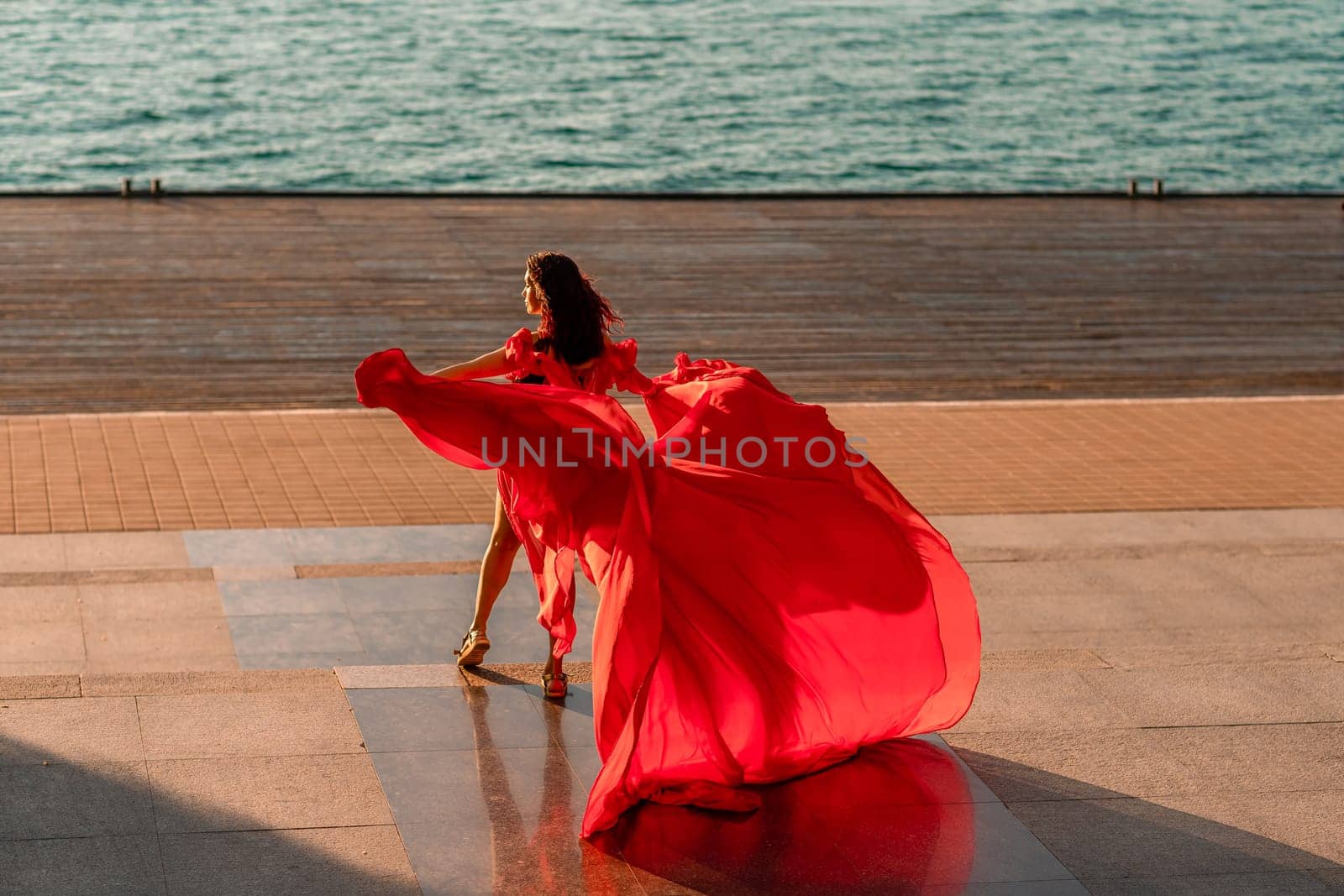 Sunrise red dress. A woman in a long red dress against the backdrop of sunrise, bright golden light of the sun's rays. The concept of femininity, harmony. by Matiunina