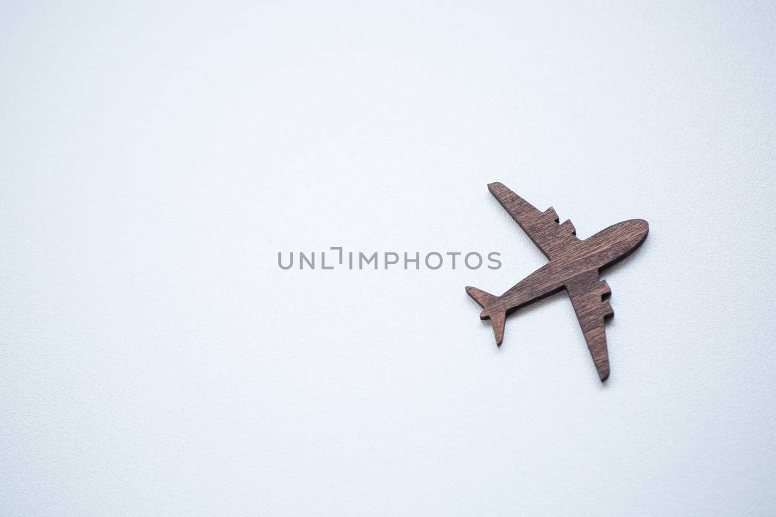 A wooden airplane figurine is glued to a wall on a white background, a place for advertising text inscription