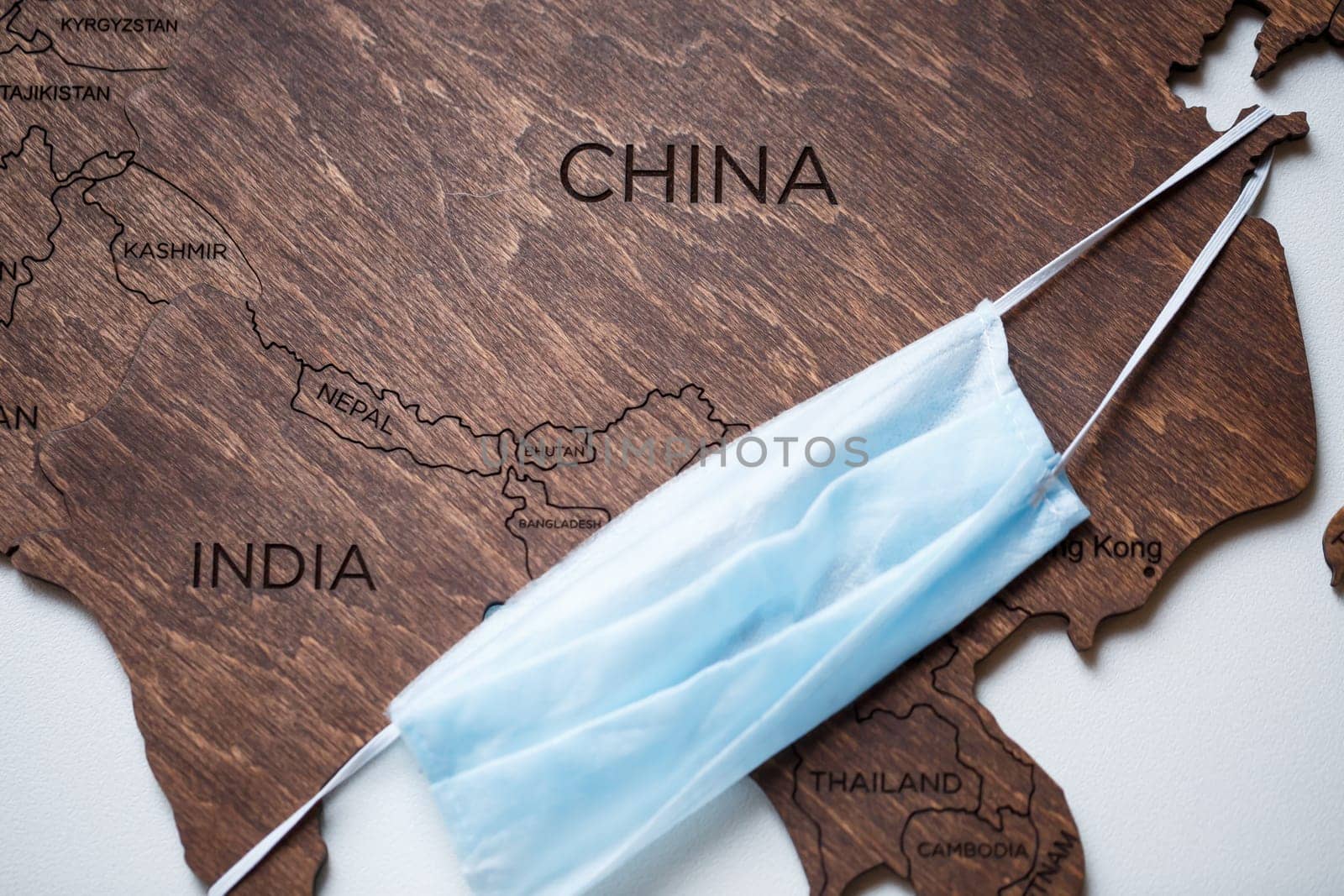 wooden map on a white background with a medical mask for protection against the virus