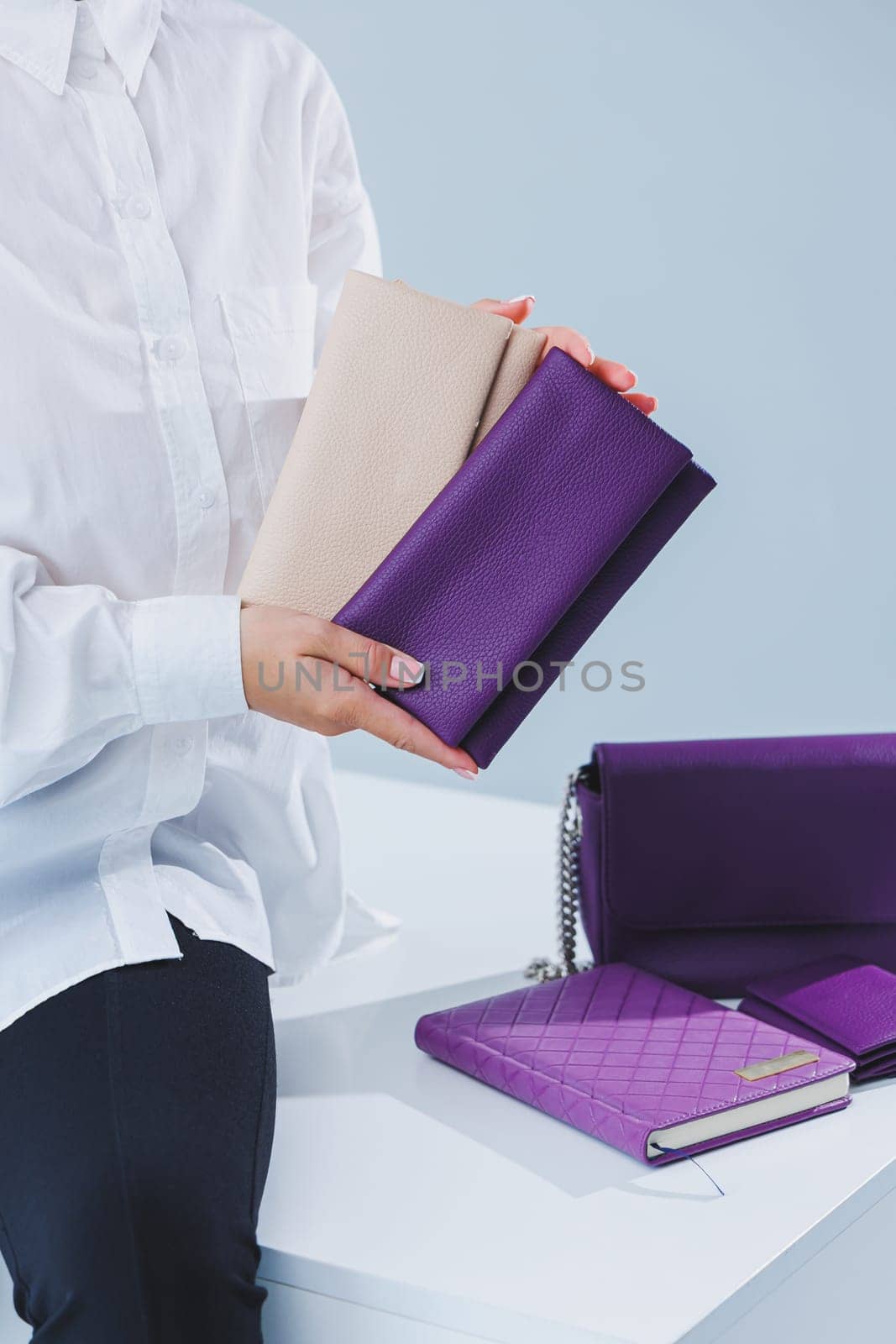 A stylish woman holds a purple leather purse in her hands. Small women's handbag