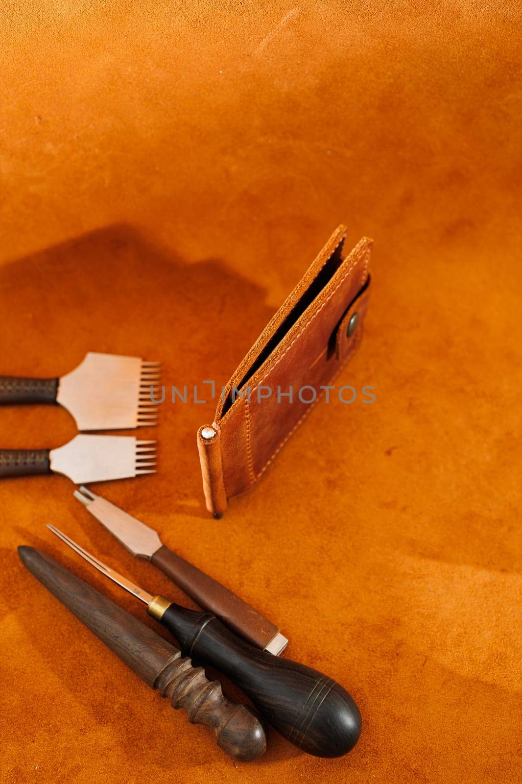 Production of handicrafts from genuine leather. Tools for making leather goods and pieces of brown leather. Production of leather products. View from above