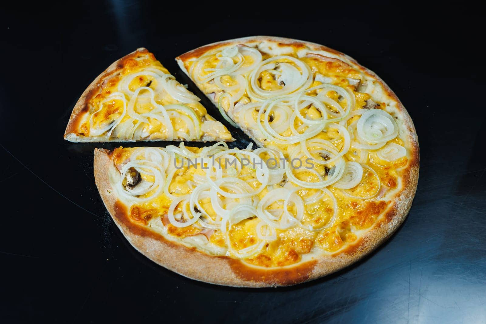 Sliced pizza with onion and meat, tomato sauce, mozzarella, onion and edge of dough, filled with cream cheese on a black background