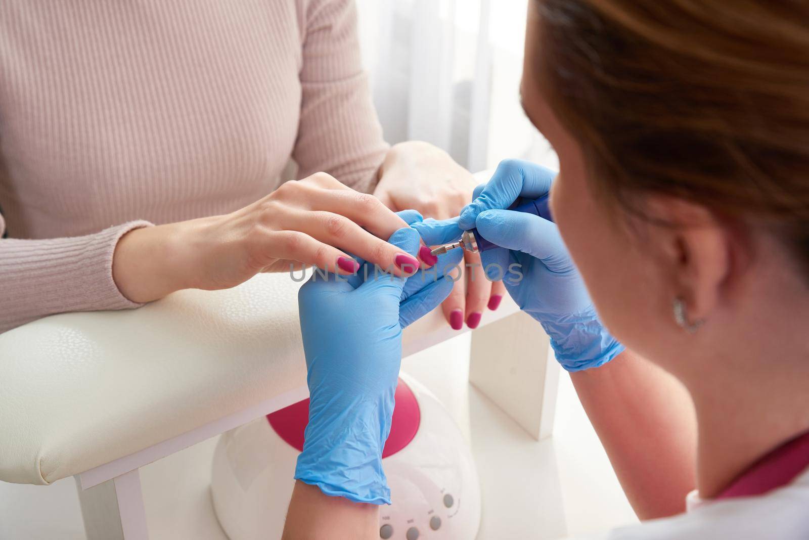 Beautician Salon, Manicure, Nails Polish Procedure. Professional hardware manicure using electric machine in beauty salon. master uses an electric machine to remove nail polish hands during manicure