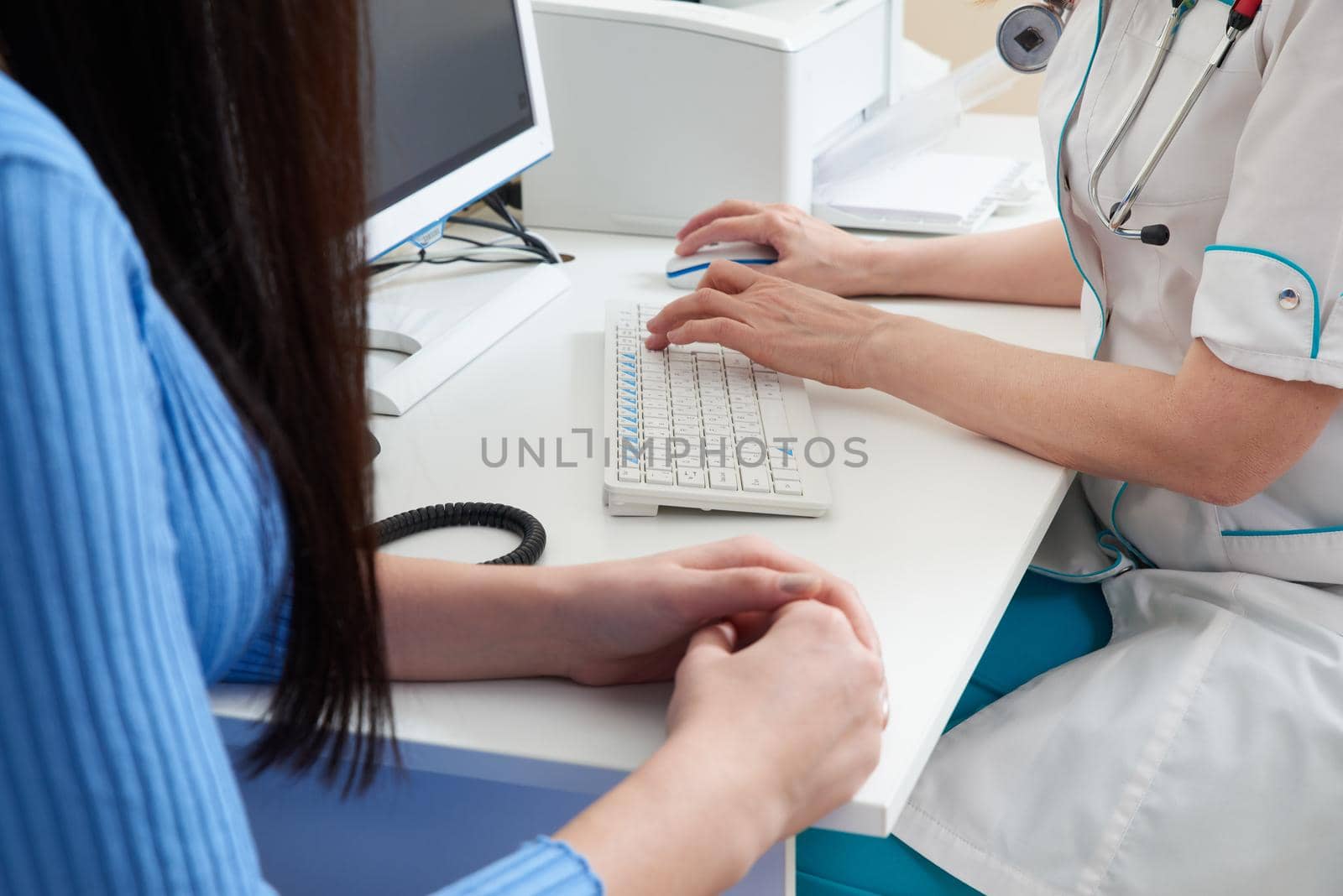 Cropped image of Young smart doctor diagnosing and giving advice to his patient while sitting together at the doctor working desk