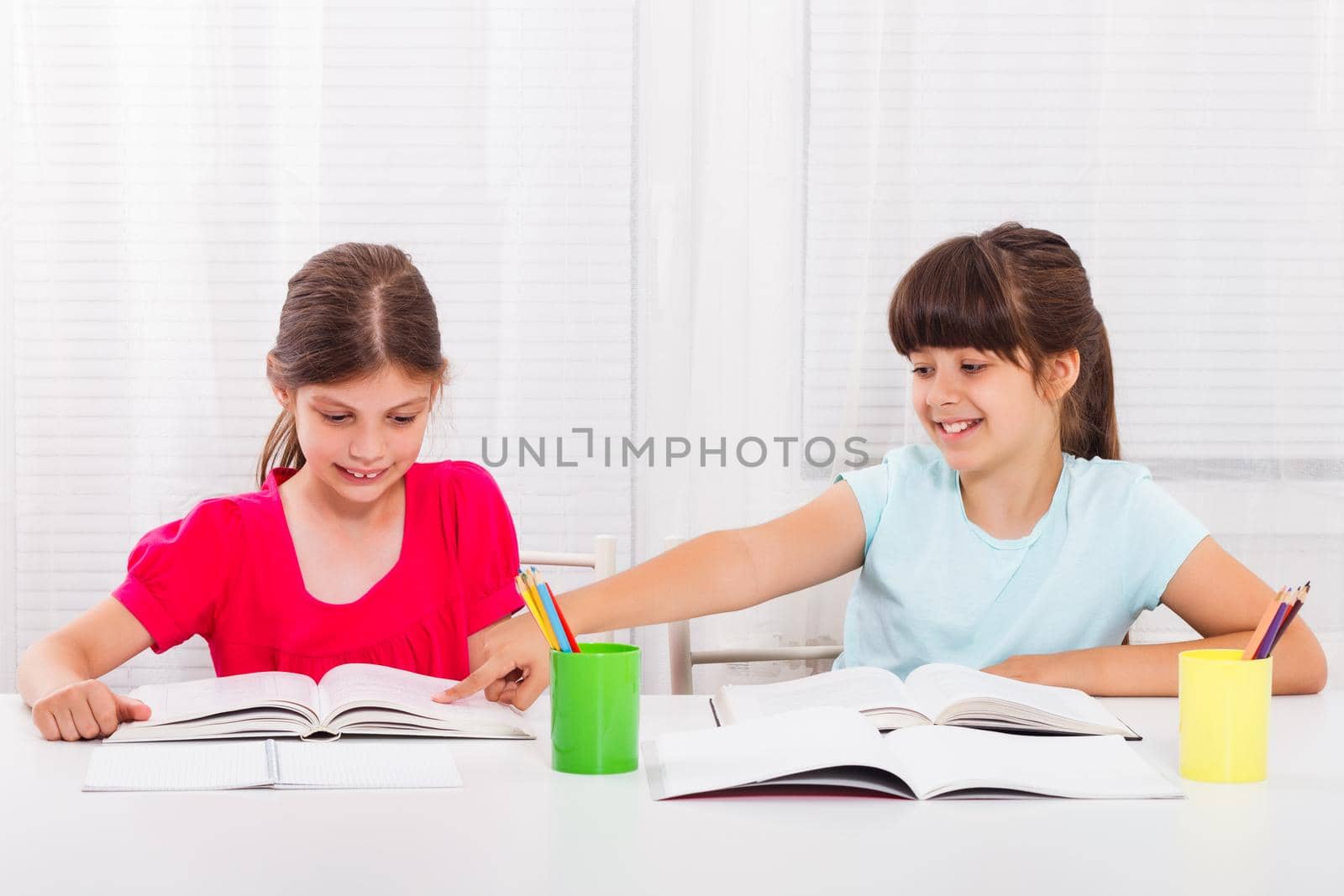 Two little schoolgirls reading and talking