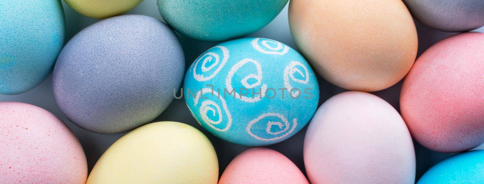 Colorful Easter eggs dyed by colored water with beautiful pattern on a pale blue background, design concept of holiday activity, top view, full frame. by ROMIXIMAGE