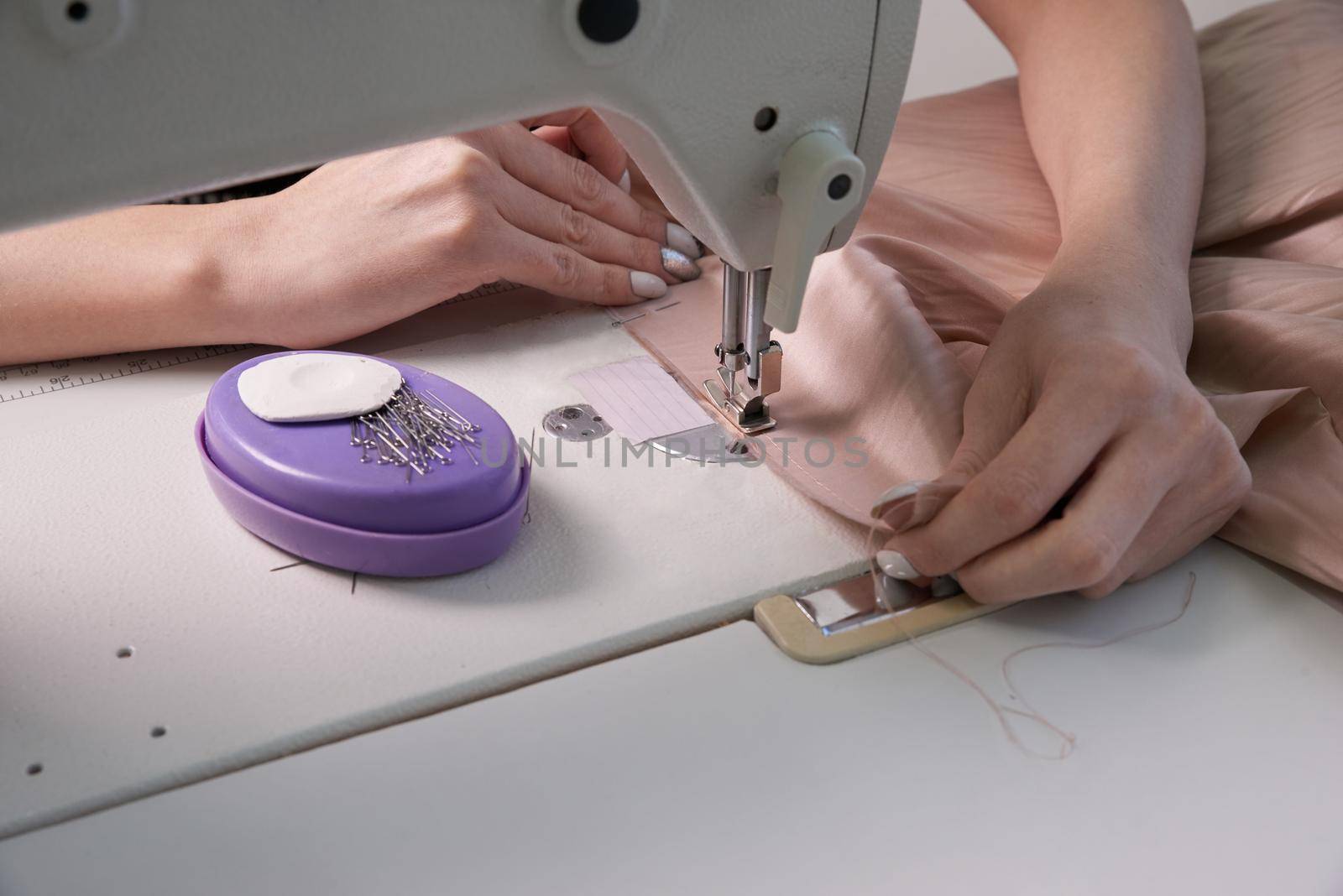 Woman using sewing machine in tailor studio or modern atelier shop