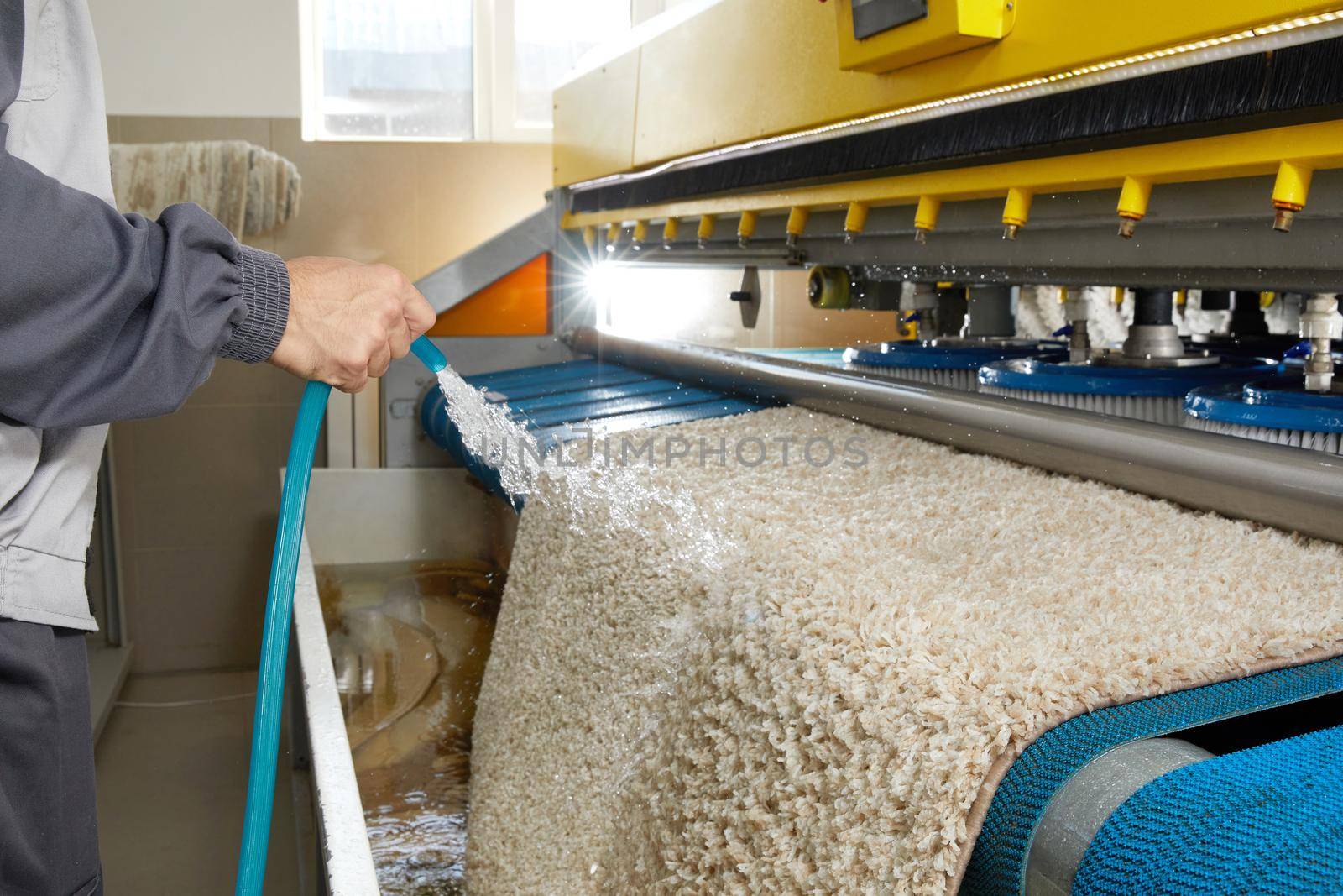 Man worker cleaning carpet on automatic washing machine equipment and dryer in the Laundry room