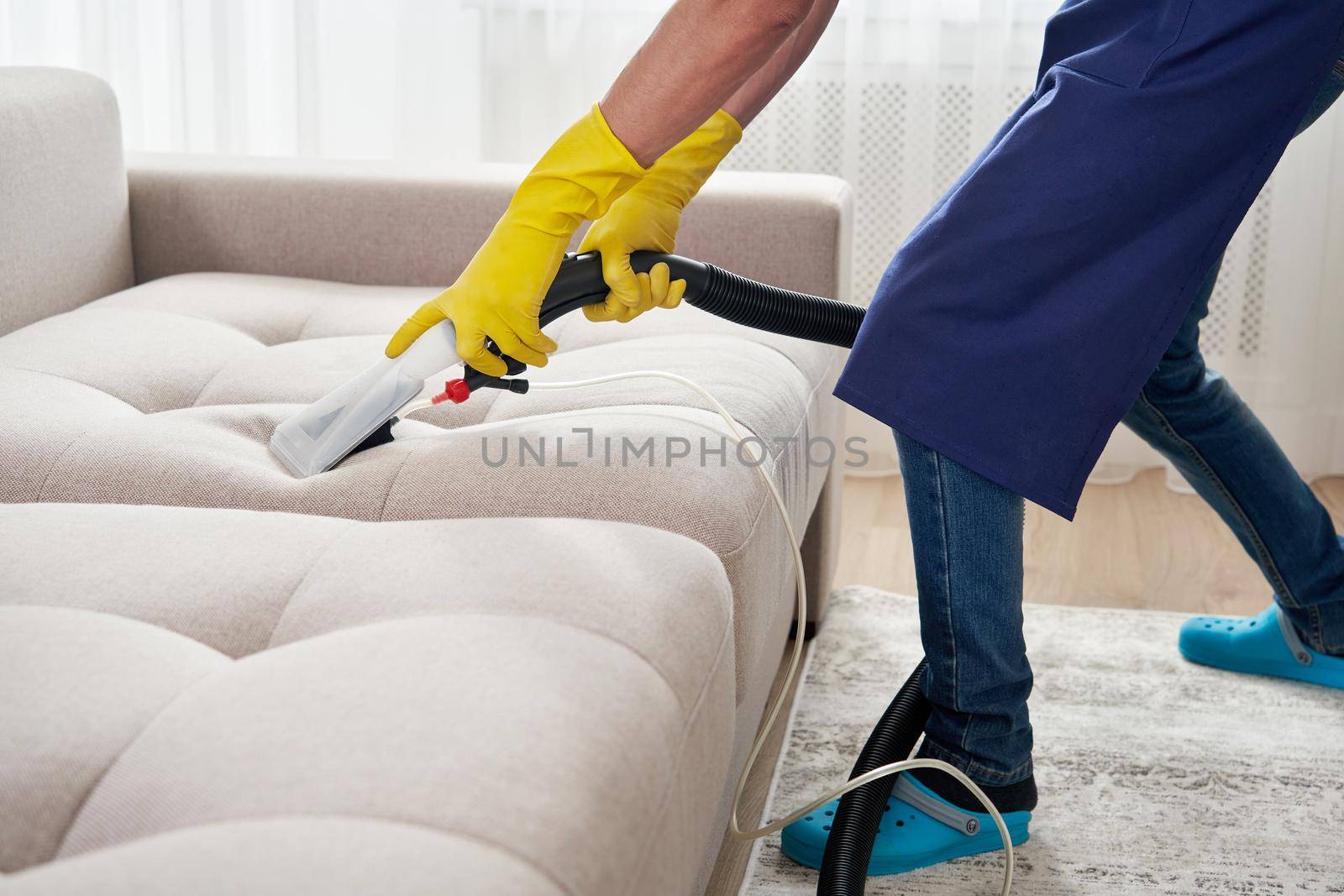 Dry cleaning worker removing dirt from sofa indoors