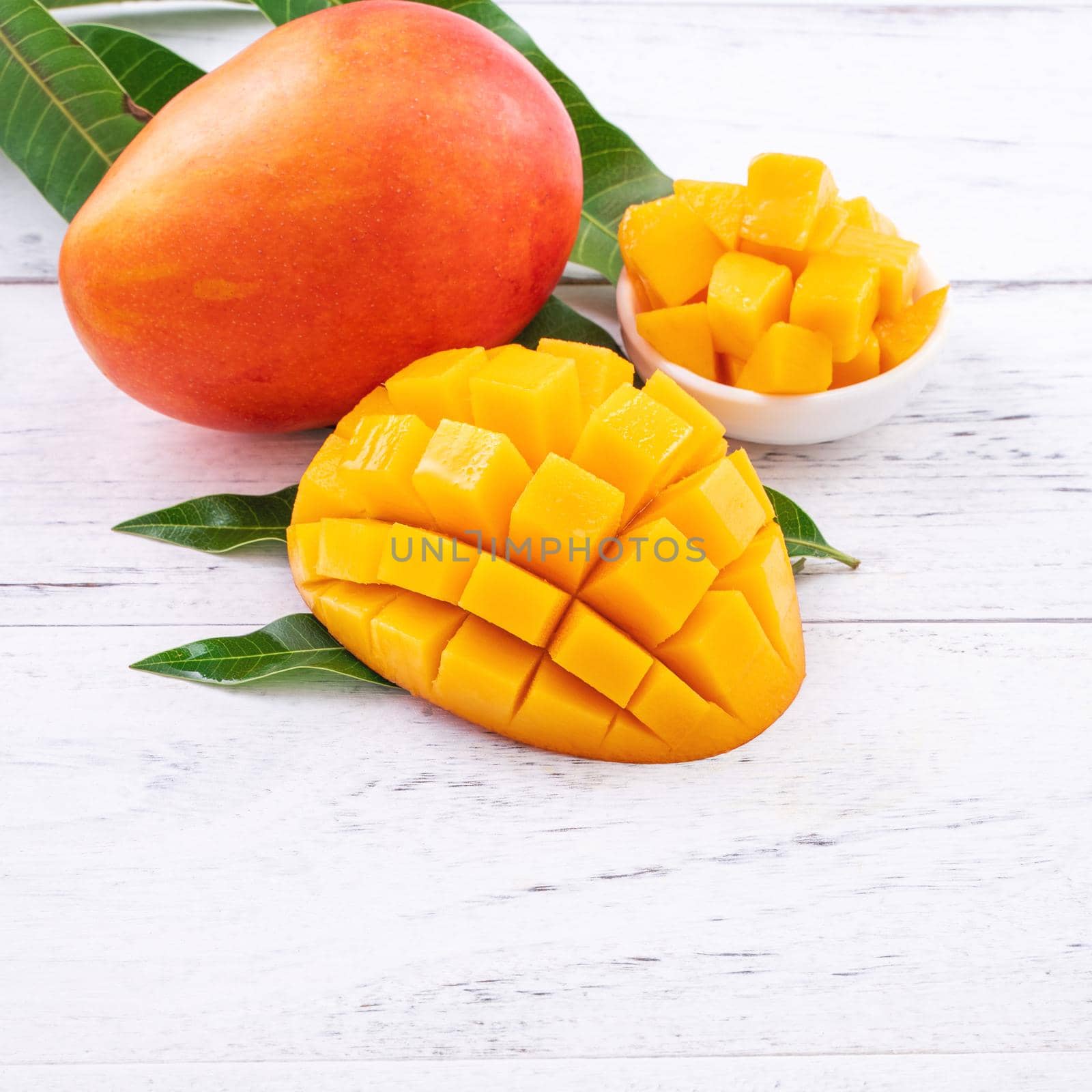 Fresh mango,beautiful chopped fruit with green leaves on bright wooden table background. Tropical fruit design concept, close up, copy space. by ROMIXIMAGE