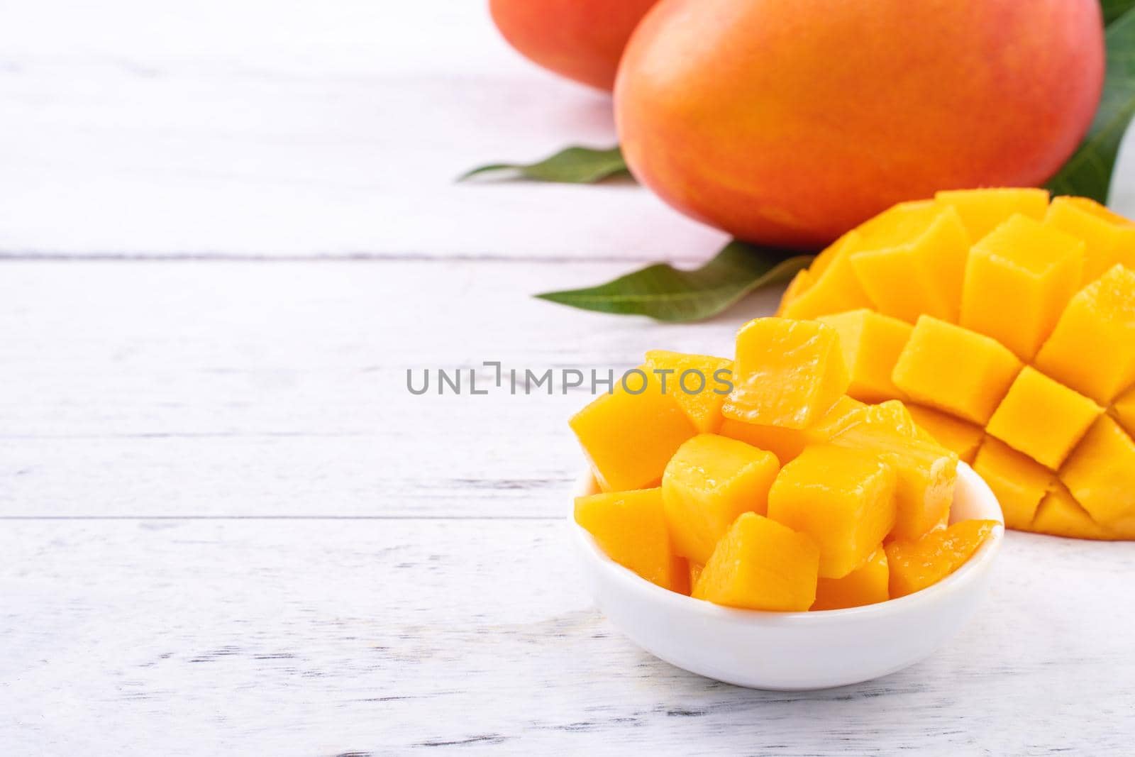 Fresh mango,beautiful chopped fruit with green leaves on bright wooden table background. Tropical fruit design concept, close up, copy space. by ROMIXIMAGE