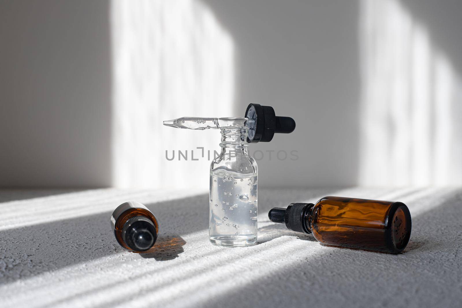 Glass bottle of mineral beauty oil with dropper for skin, hair. Product packaging serum on a white background. Women's cosmetics skin care cream with shadows. Copy space