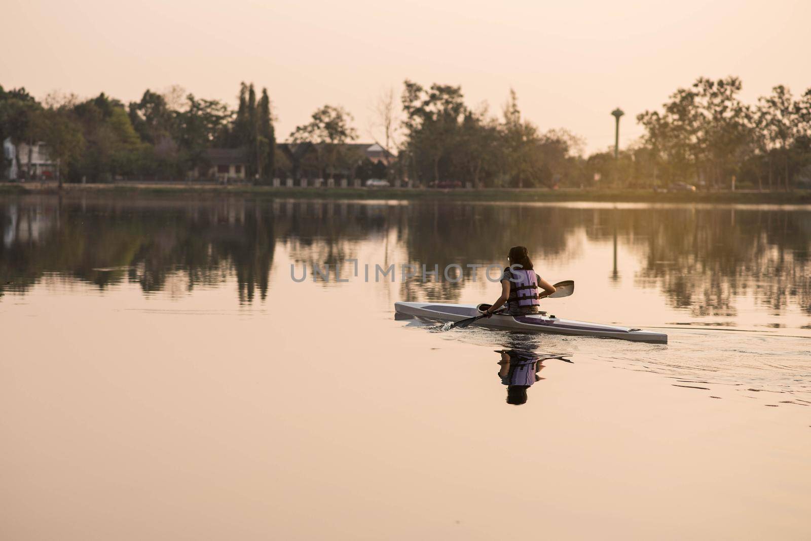 the girl training kayak sails in the river sunset by Wmpix