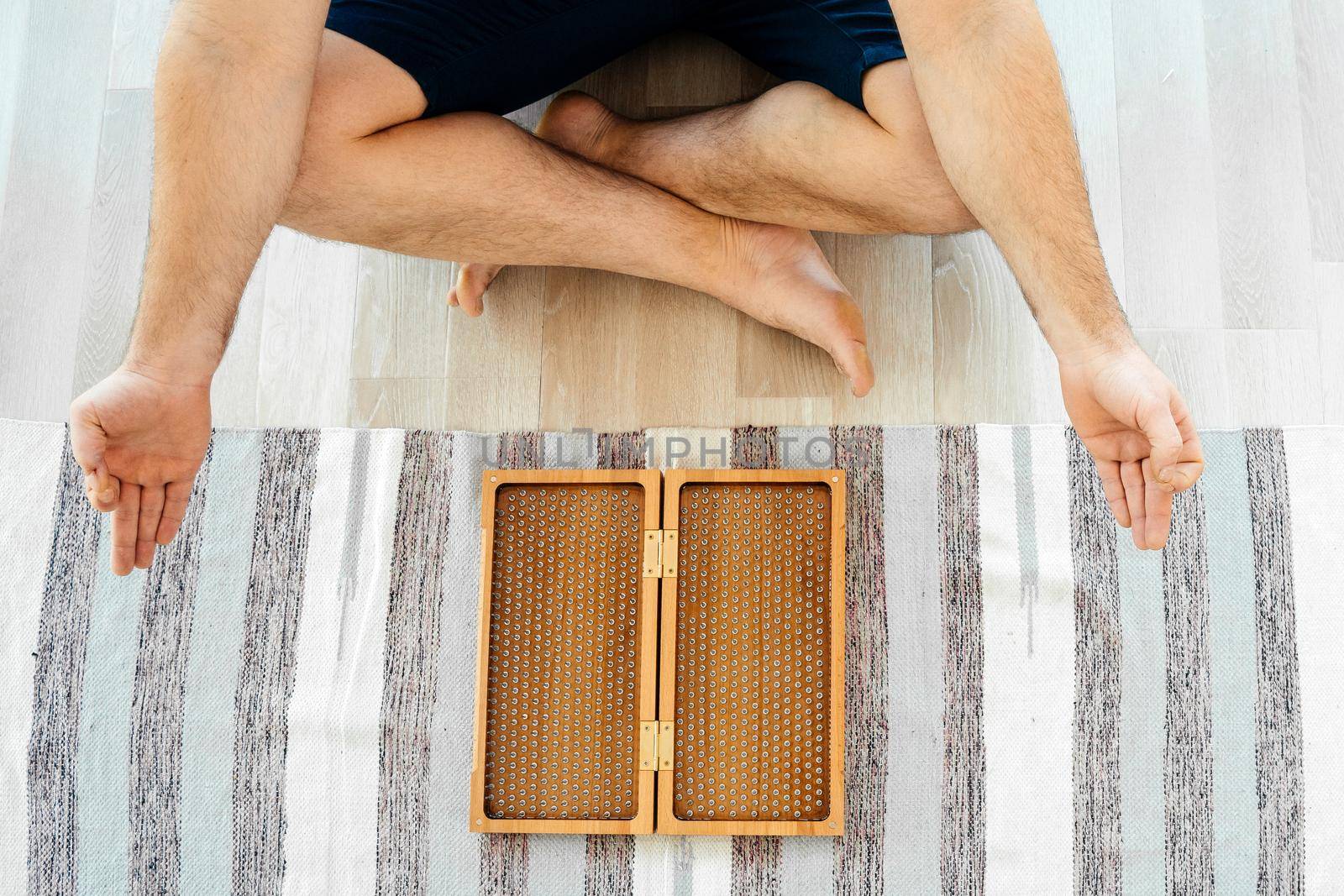 Man exercising yoga meditating and sitting on the floor near sadhu board